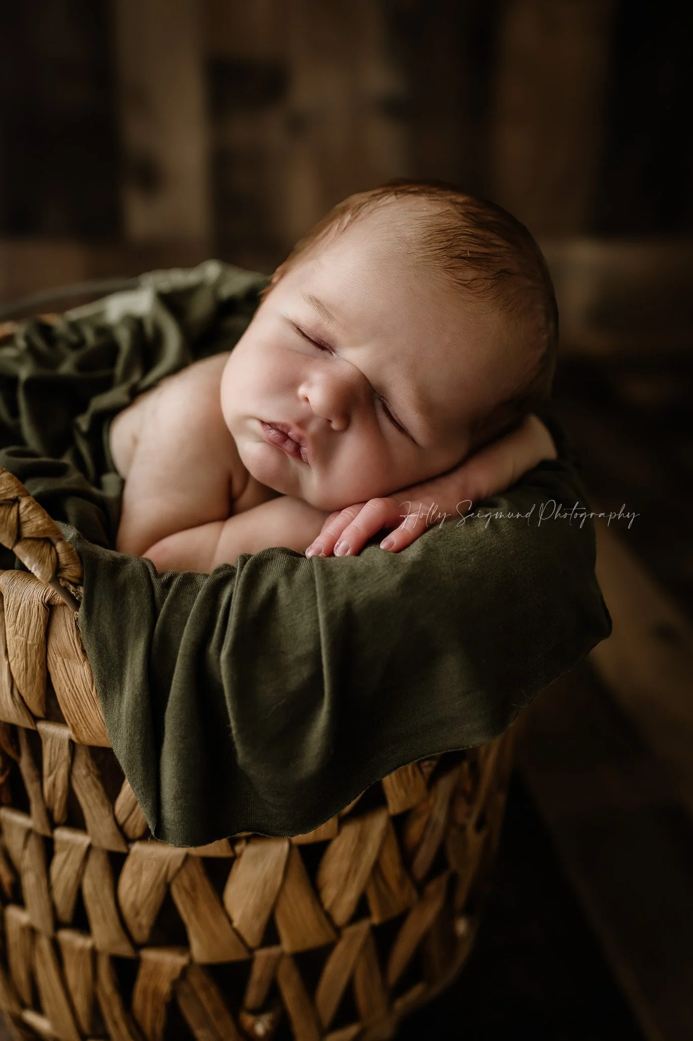 Newborn baby boy posed in a basket with a wood backdrop in a Lee County Texas studio