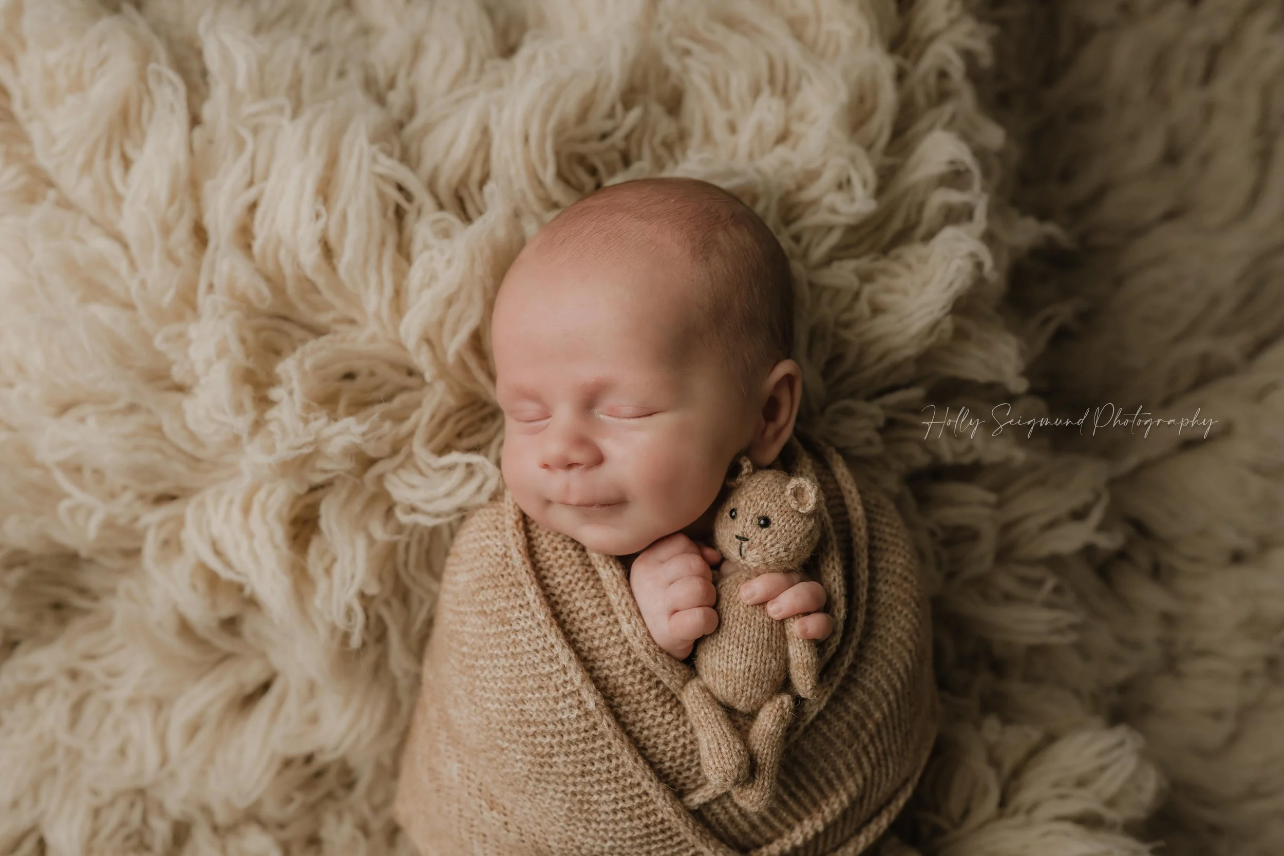 Baby boy with a teddy bear wrapped in tan during a in-home newborn session in Bastrop County