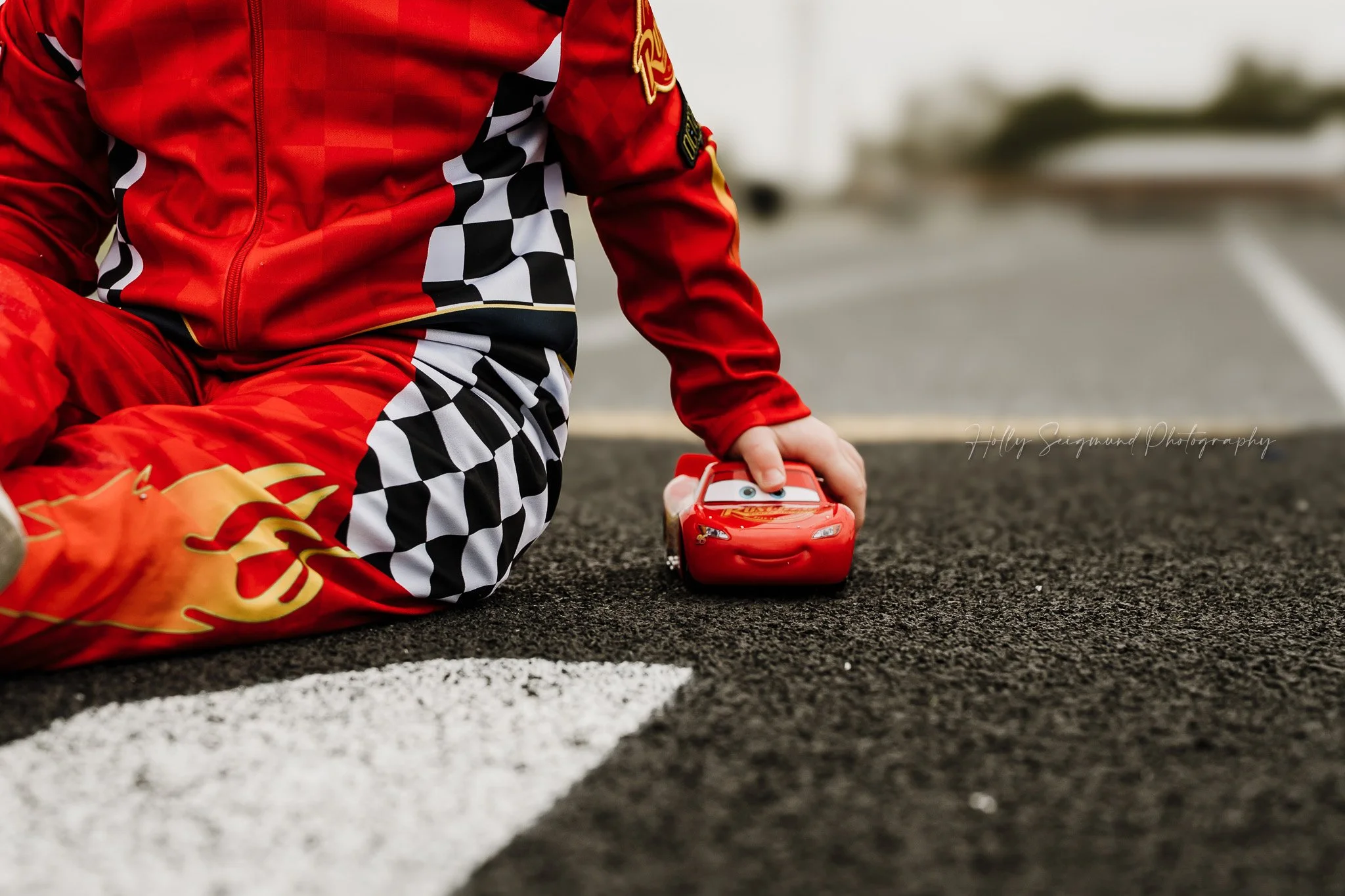 birthday boy posing with race car theme props during a 4th birthday session in Giddings TX