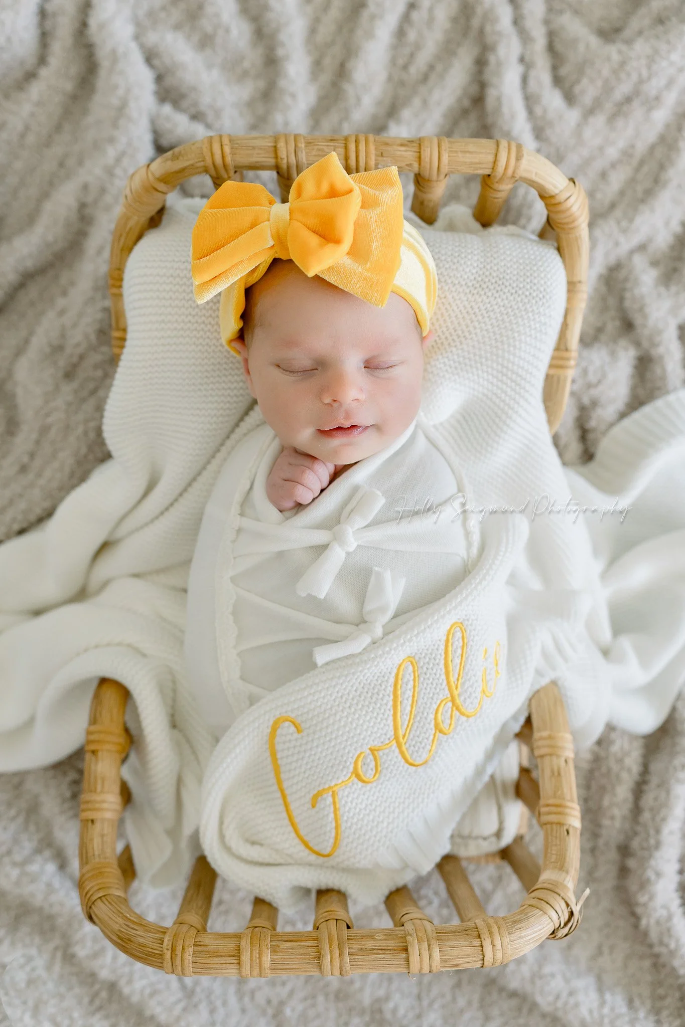 In-home newborn session in Central Texas with a baby in a wooden bed with a yellow bow