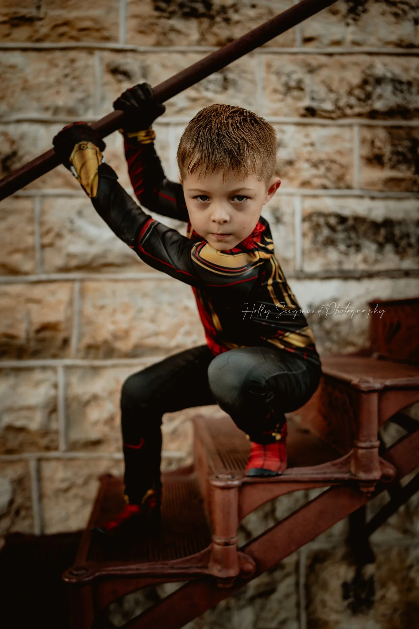 young boy in Spiderman outfit crouching in action pose at outdoor birthday photoshoot in Georgetown Texas