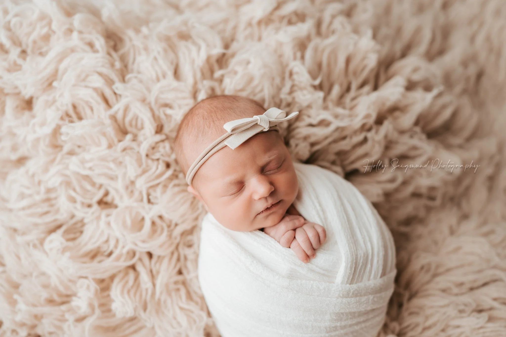 newborn girl on Suede Tan Flokati with white bow 78947