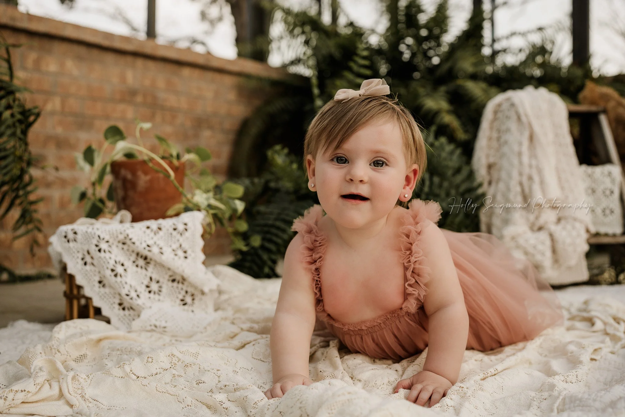 Boho girls first birthday photo session in dusty rose tutu dress with pink bow on white vintage crochet linens