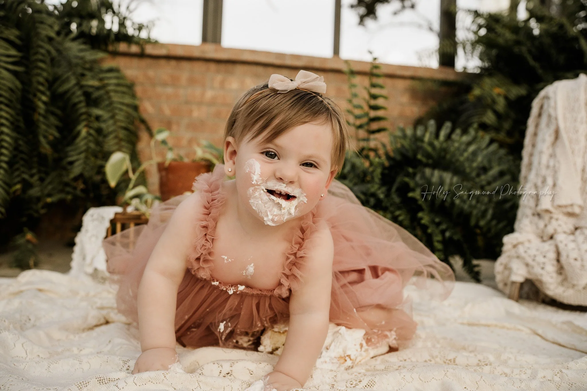 First birthday cake smash photo session with baby girl wearing a blush tulle dress