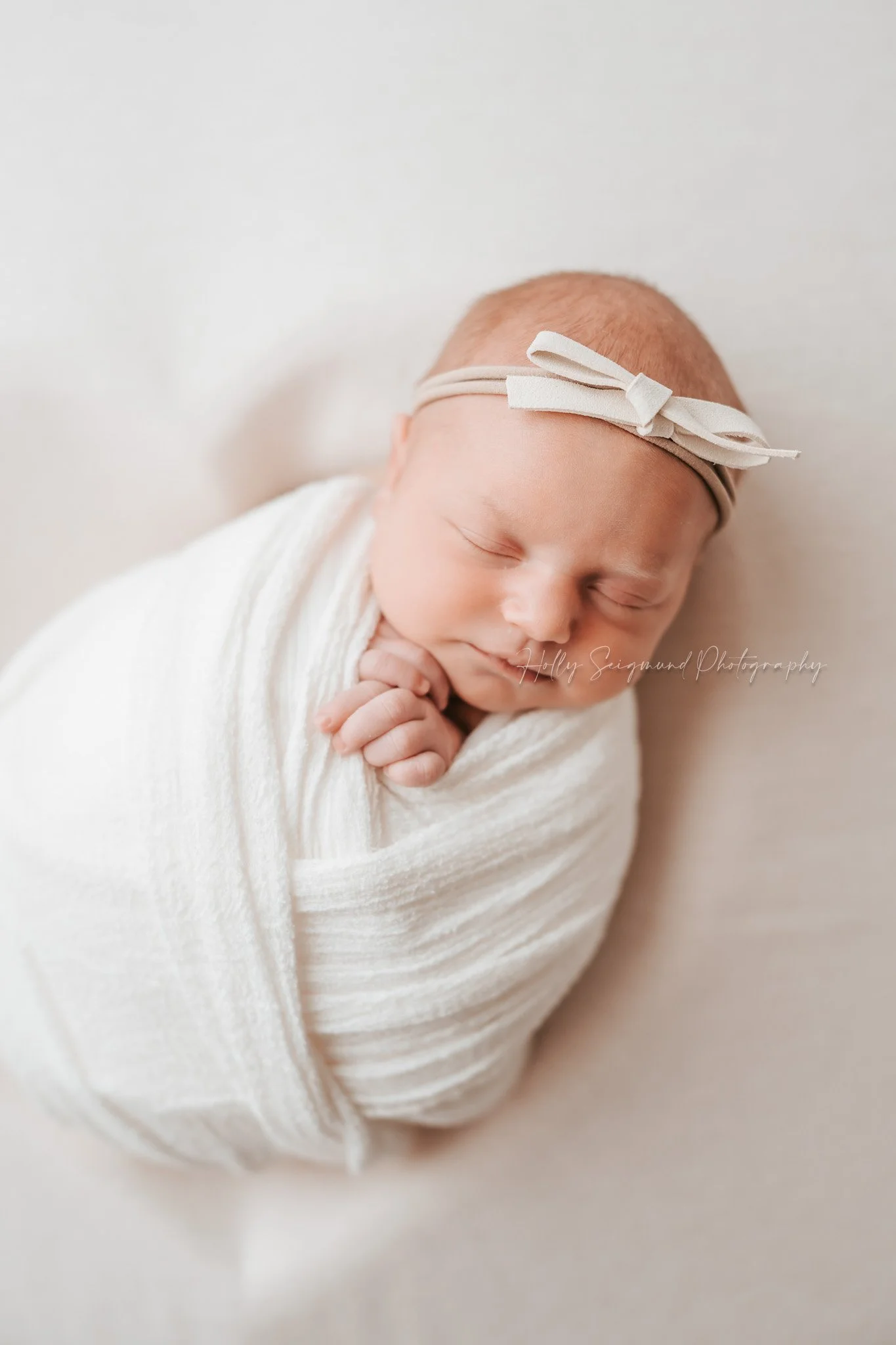 Central Texas Newborn on white heart backdrop with white wrap and white bow