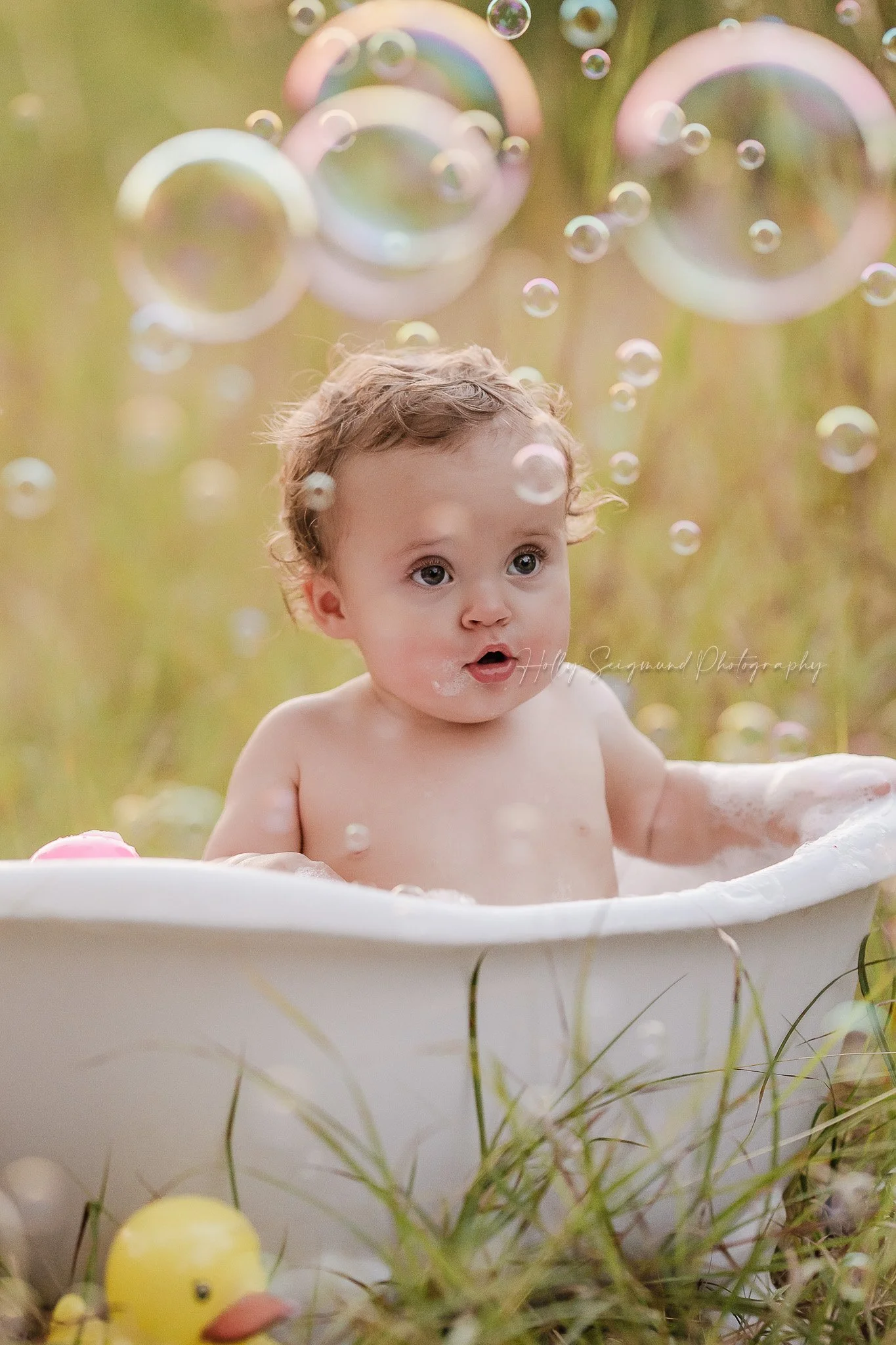 Baby in a bubble bath in the grass with bubbles in the air