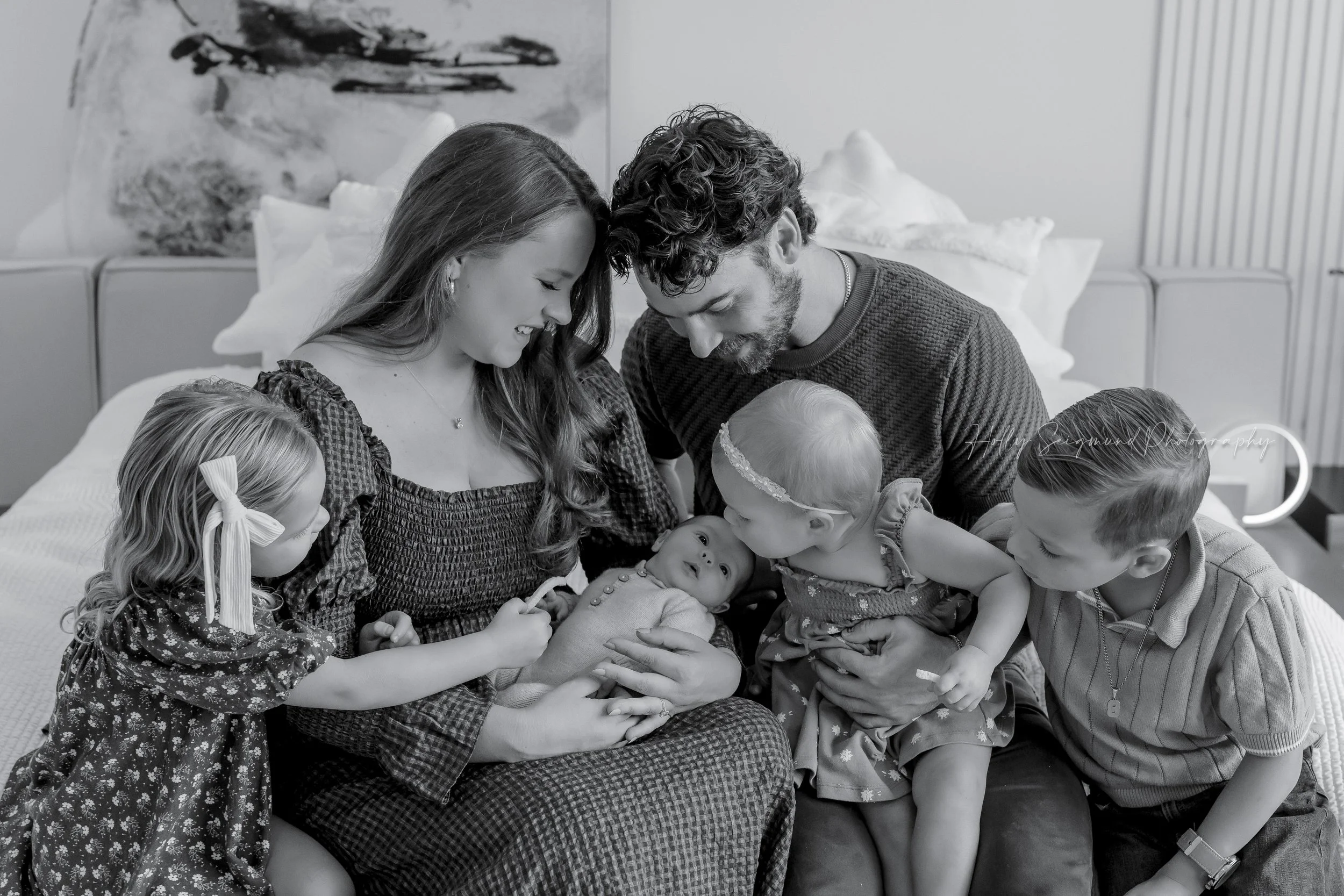 Family smiling and looking at newborn baby girl during a in-home family newborn session in Dripping Springs, Texas