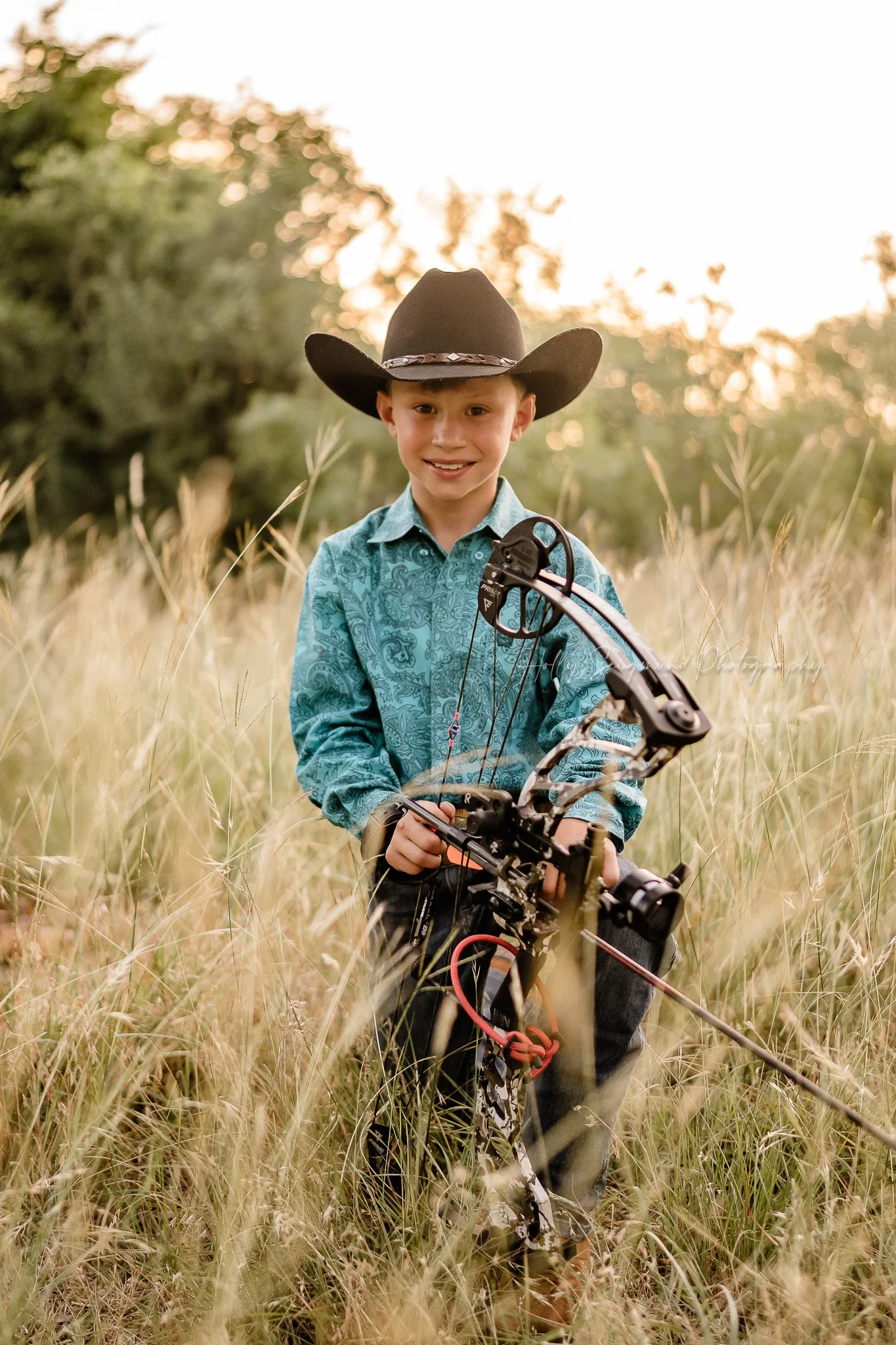 birthday boy posing outdoors with a bow during a hunting themed photoshoot in Lee County TX