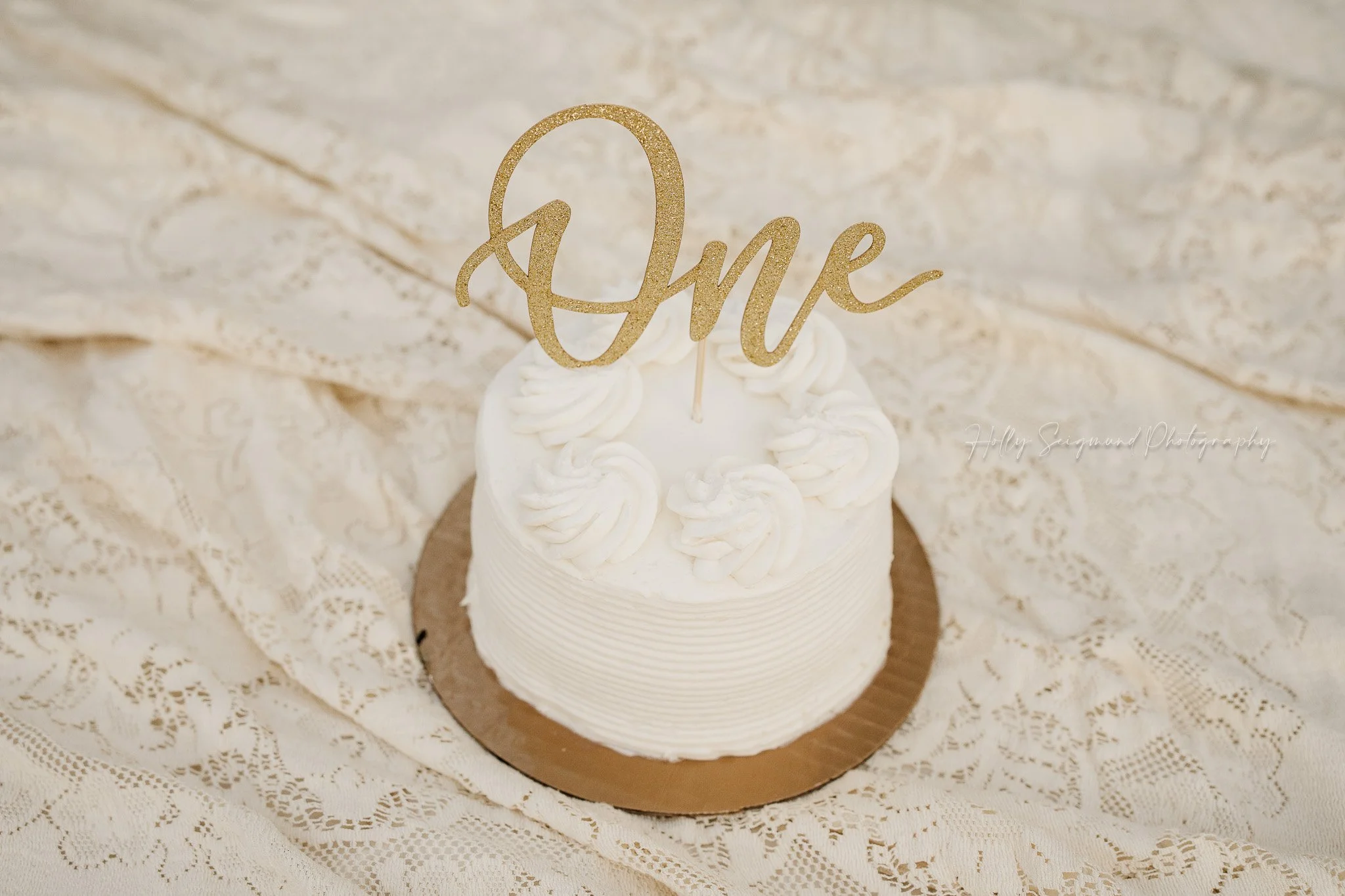 Simple white first birthday cake on vintage lace linens photographed in Central Texas