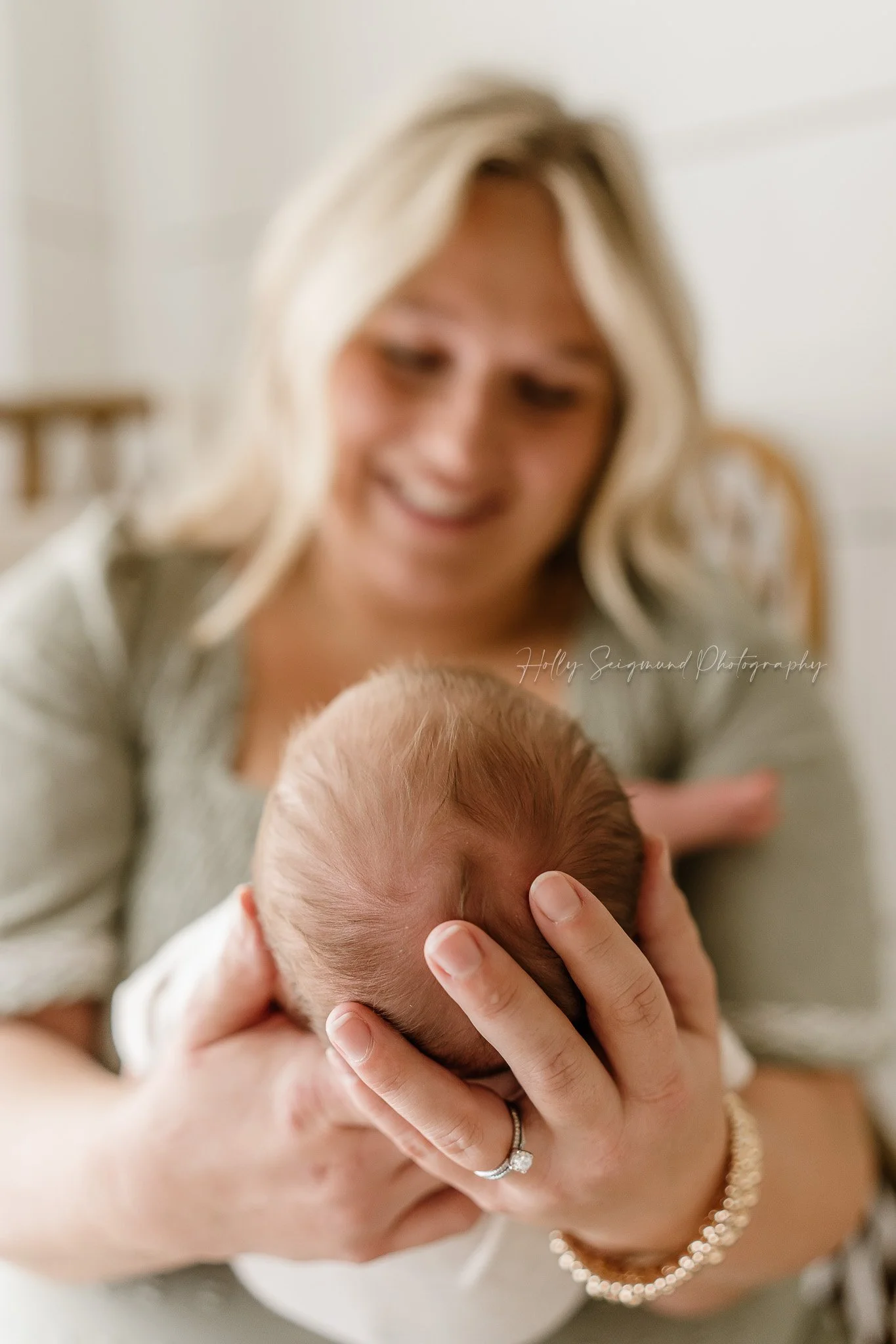 Mom looking at baby with his head in her hands in a natural light studio in Lexington, Texas