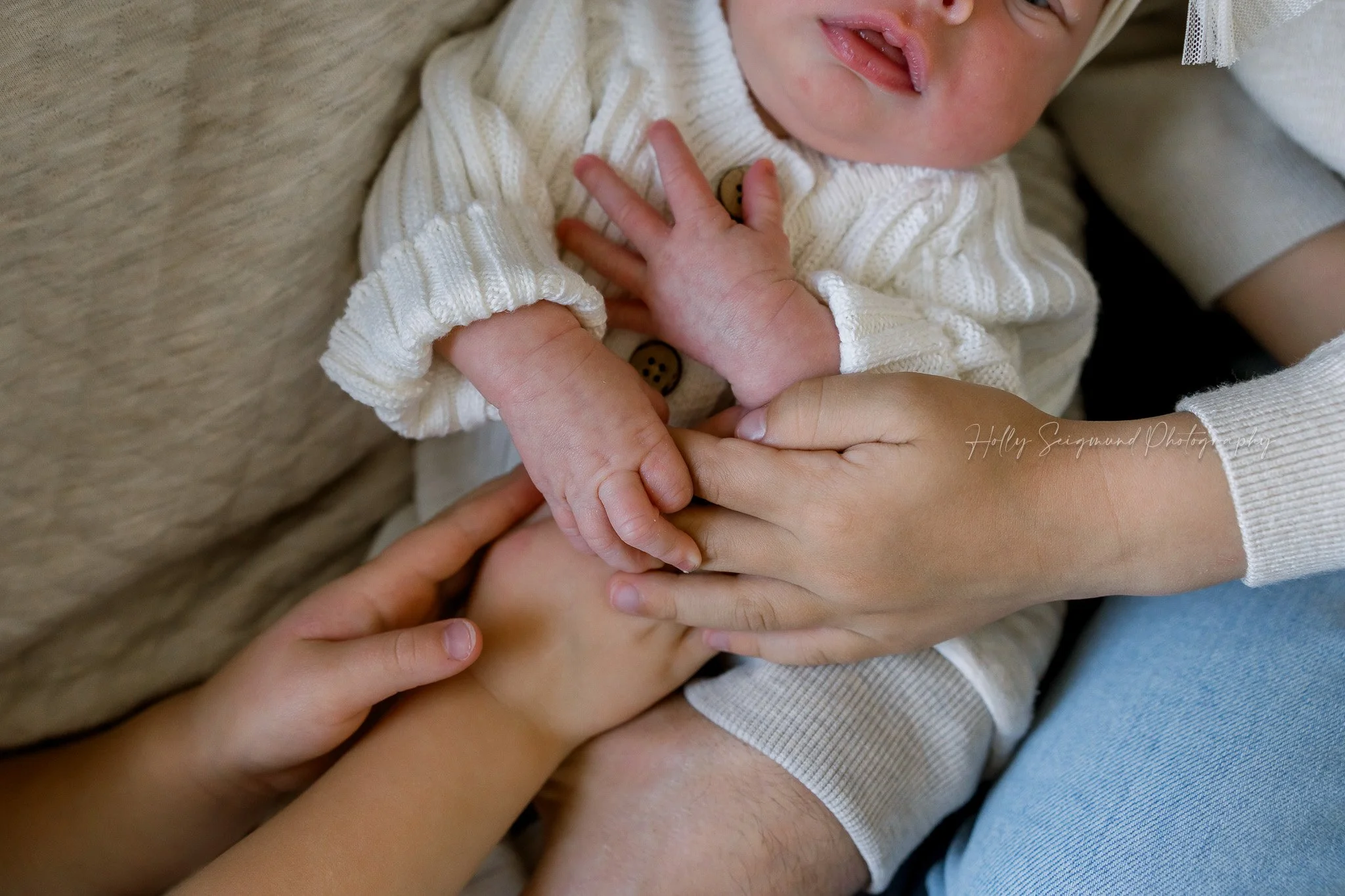 Family holding newborn baby hands during an in-home newborn session in Central Texas