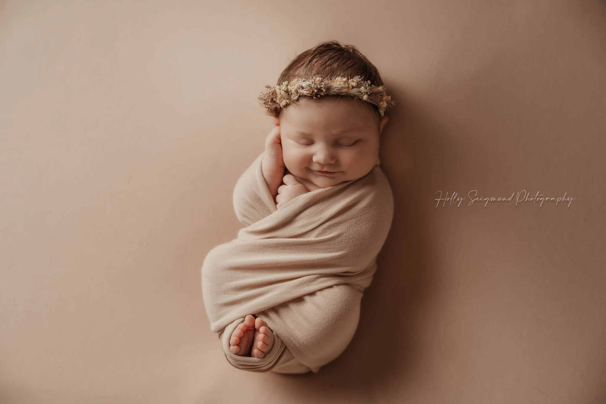 Newborn girl with a boho floral crown and a criss cross wrap with a matching background in Lee County Texas