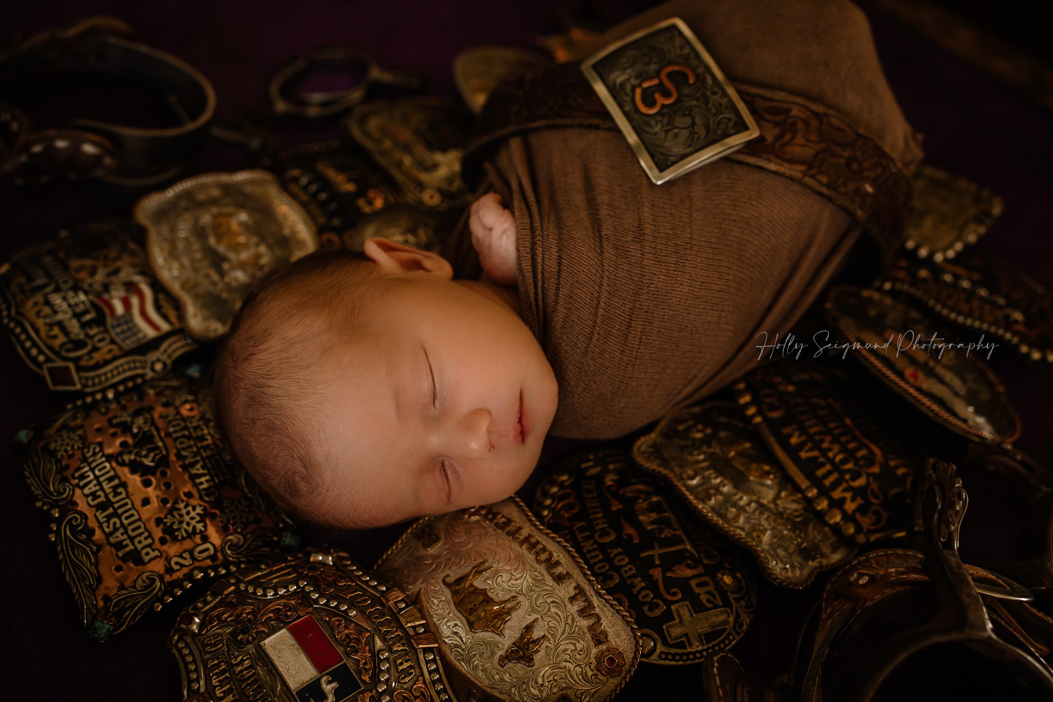 Newborn baby boy with his dad's Central Texas rodeo belt buckles 