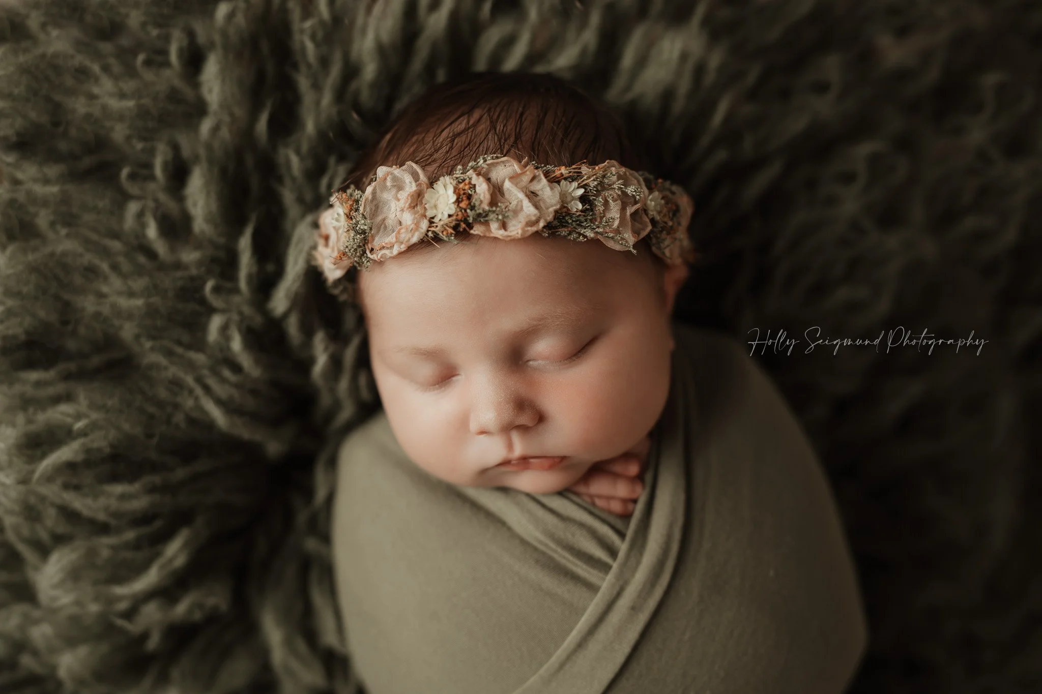 Newborn girl with boho pink and green floral crown, laying on a Conifer Green Flokati in a Central Texas Photography studio