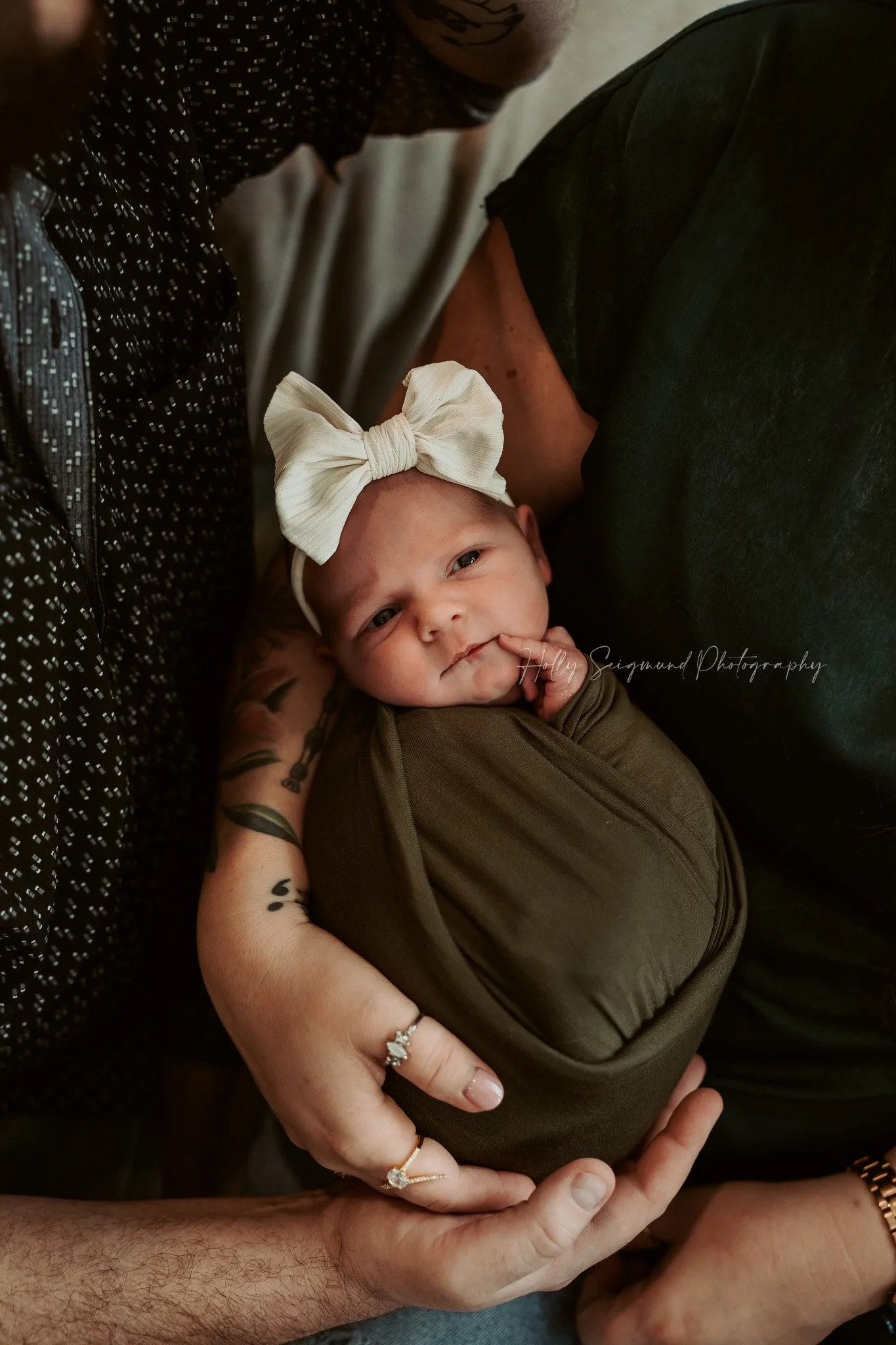 Newborn girl wrapped in green with a white bow in an in-home newborn session with moody tones in Central Texas