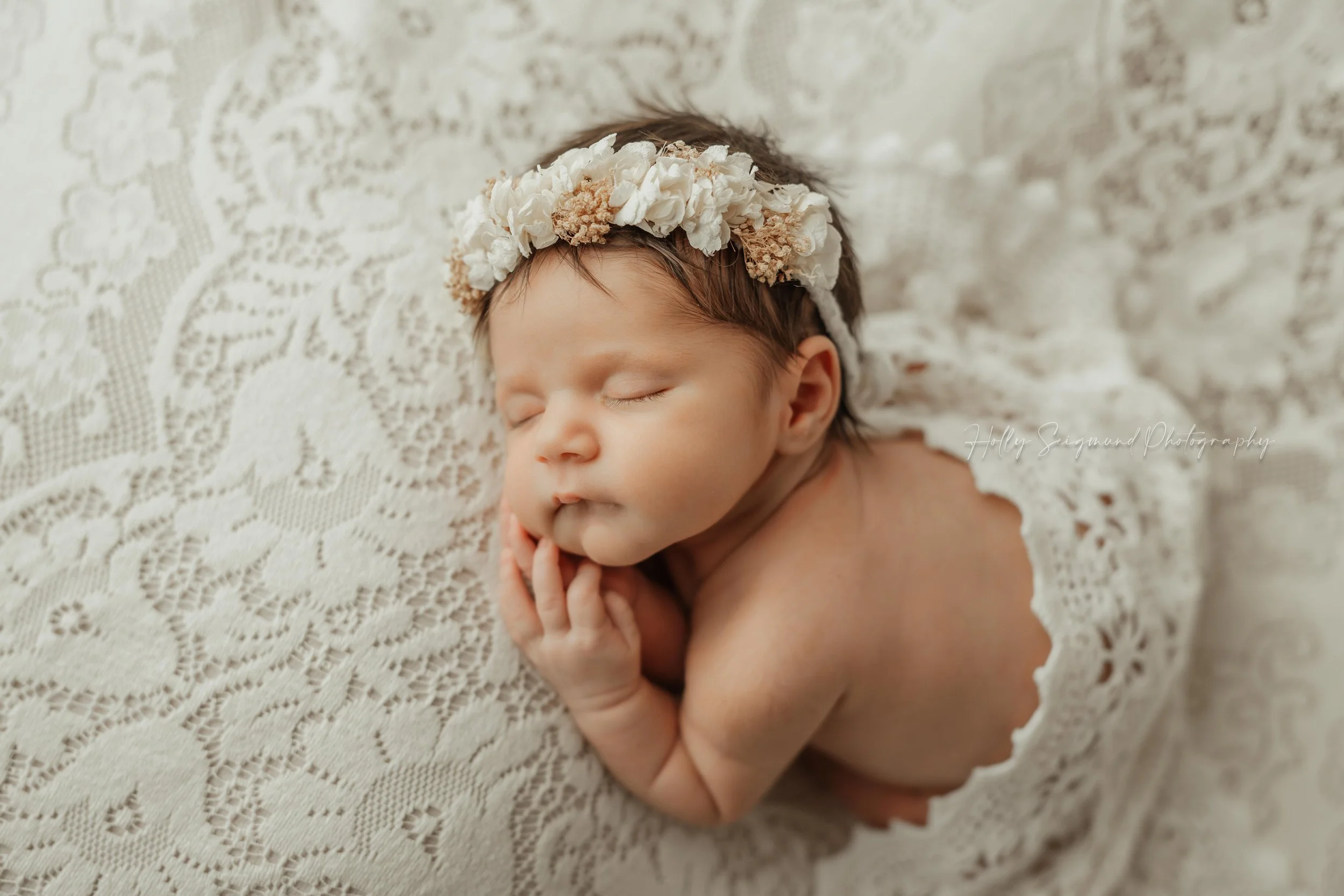 Studio newborn session featuring a baby girl with a cream colored floral crown, laying on vintage lace in Lee County Texas