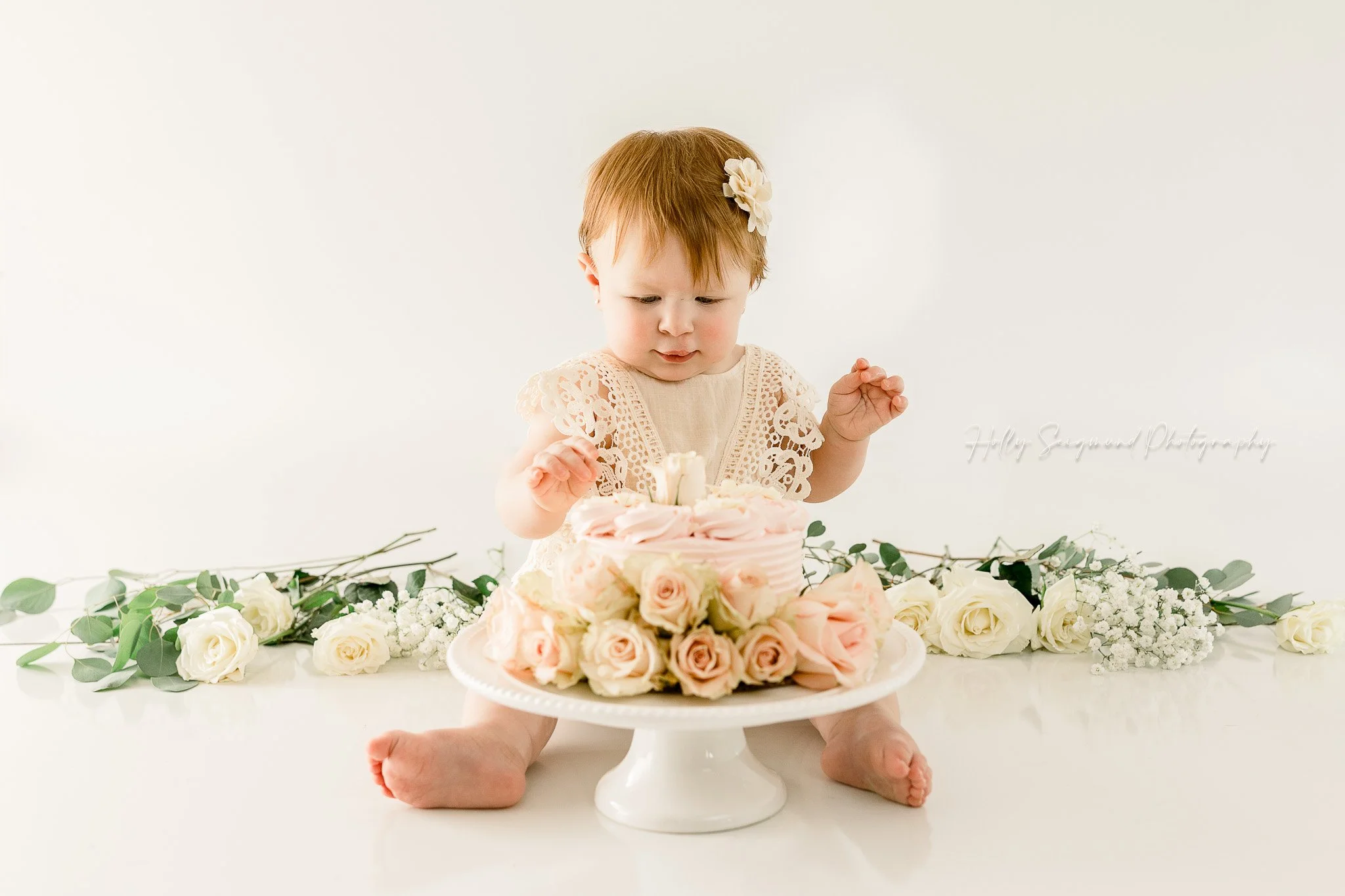 simple white and floral 1st birthday smash cake session in studio in Central Texas