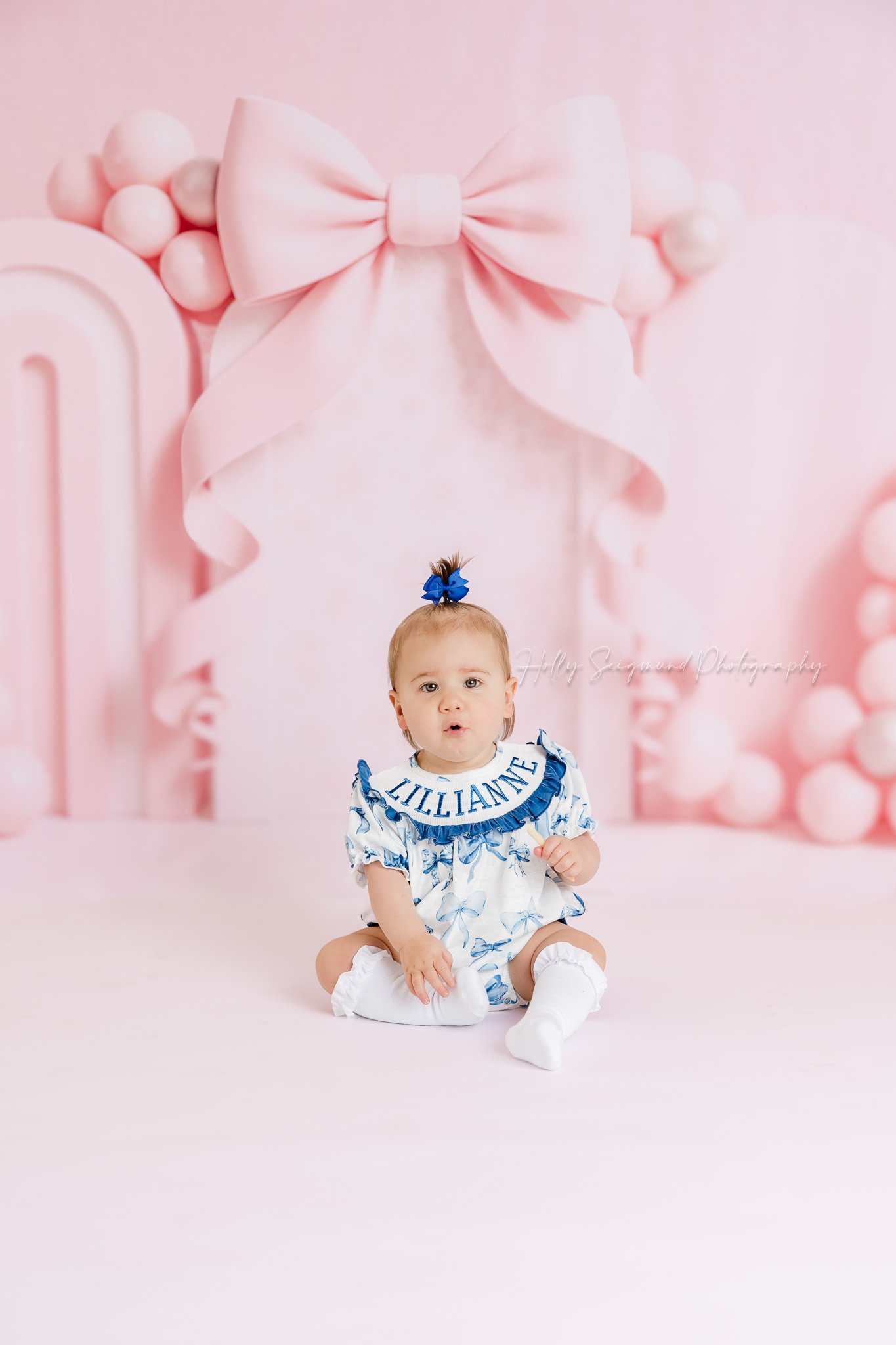 Girls first birthday photos with a pink bow background in studio in Lee County, Texas