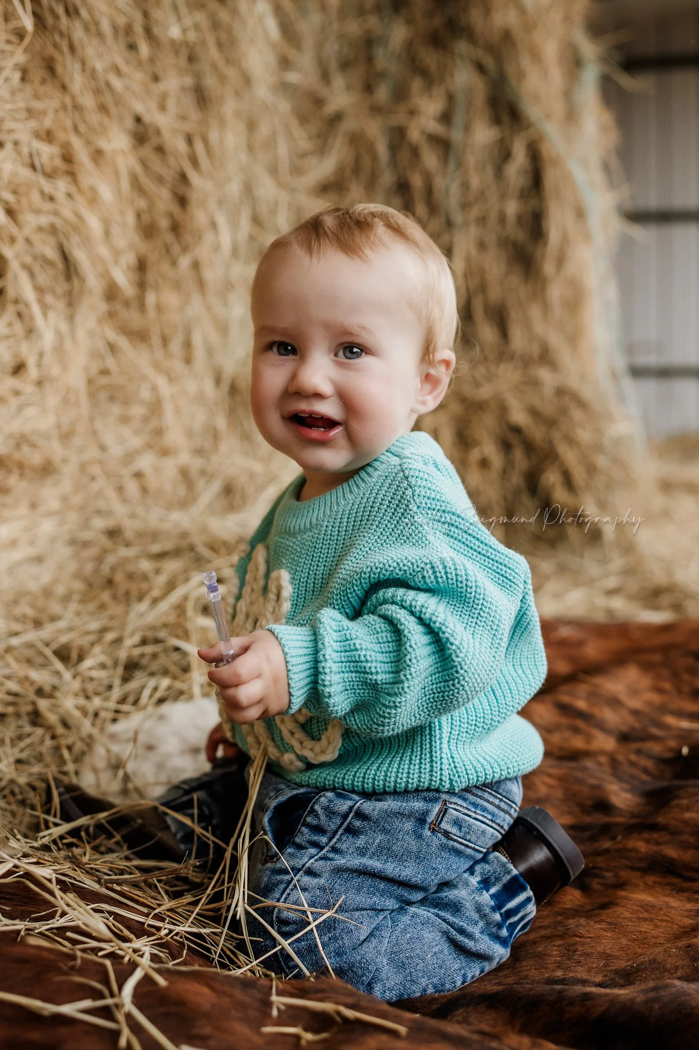 Western themed first birthday photos in front of the hay bales in the barn in Central Texas