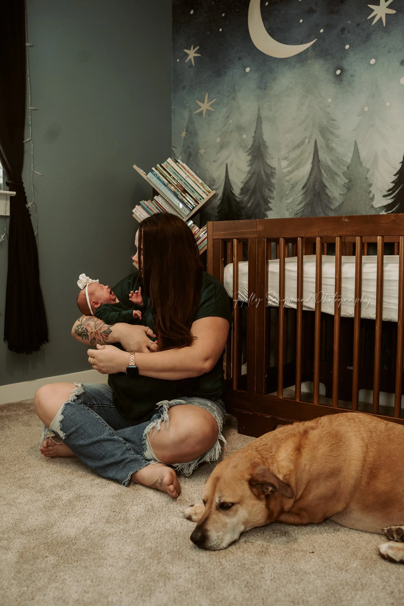 Mom and newborn baby on the floor in front of crib in nursery with the dog in Central Texas