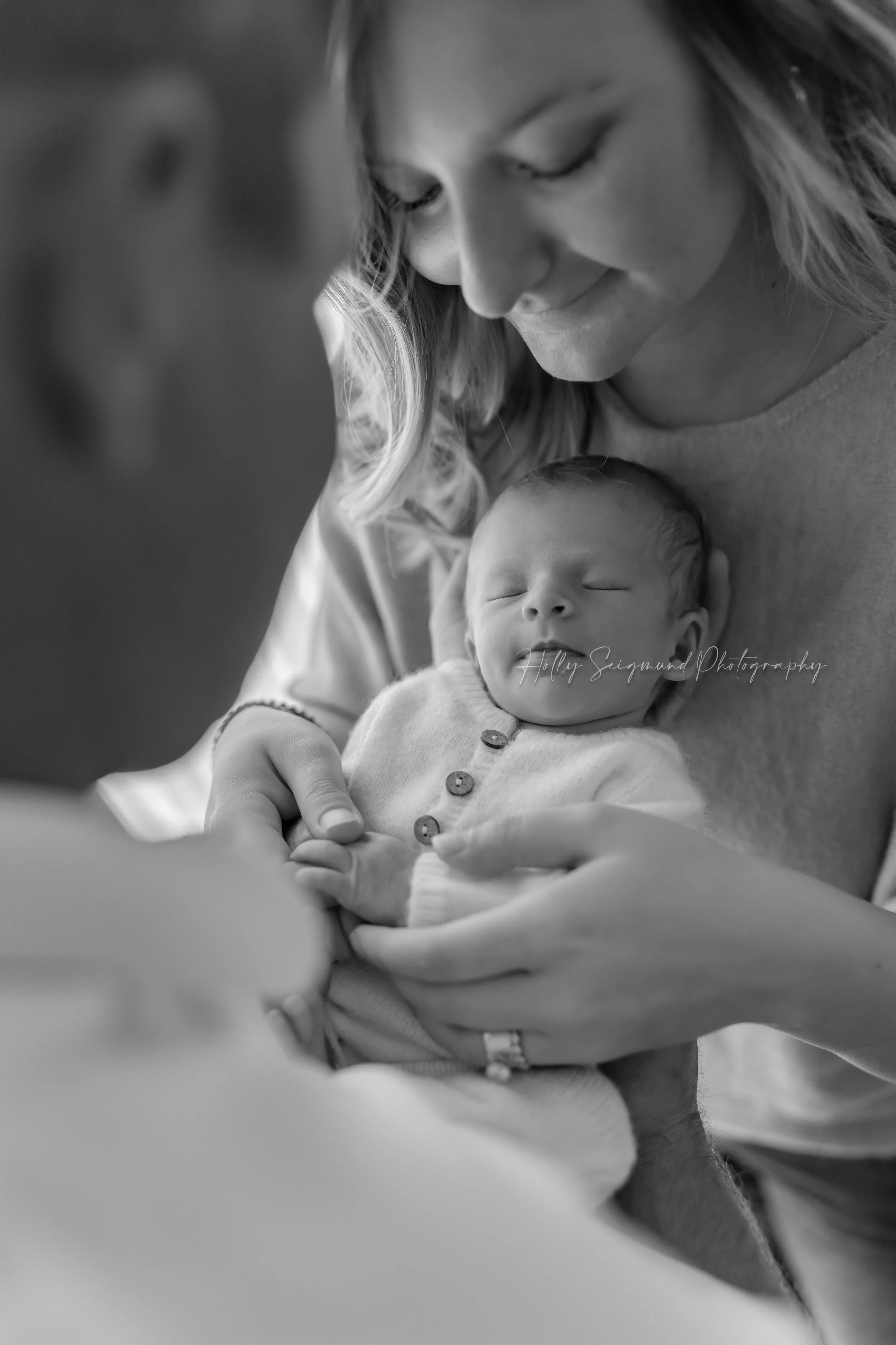 Black & White photo during a Family newborn session serving Bastrop, Texas featuring a mom and dad holding a baby girl dressed in white