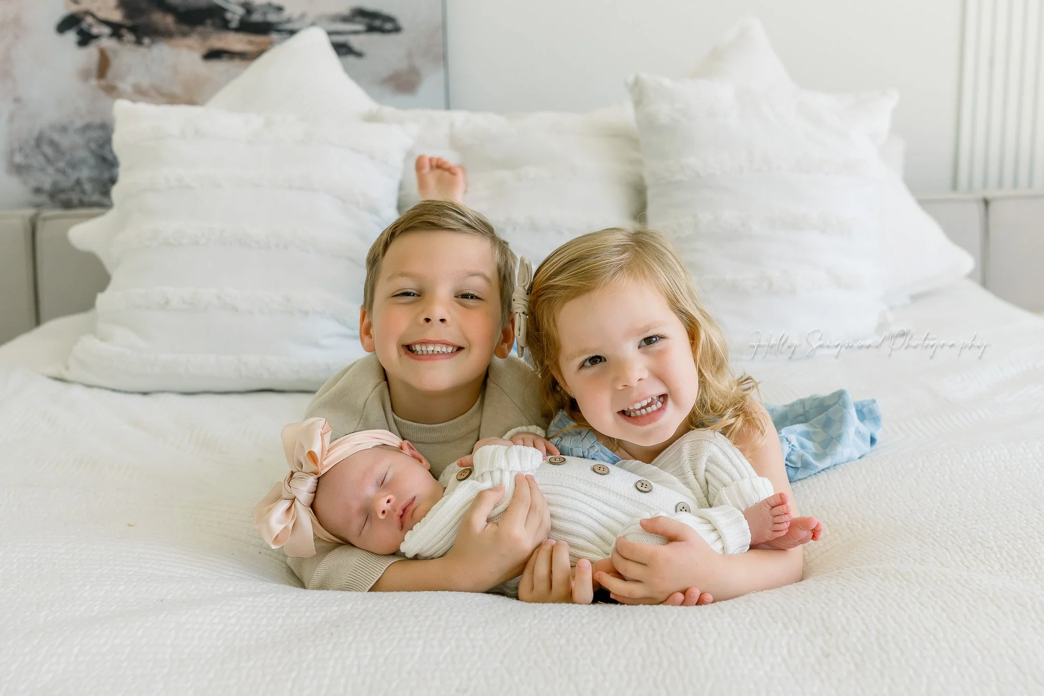 Siblings and newborn sister on a bed during a lifestyle newborn session in Central Texas