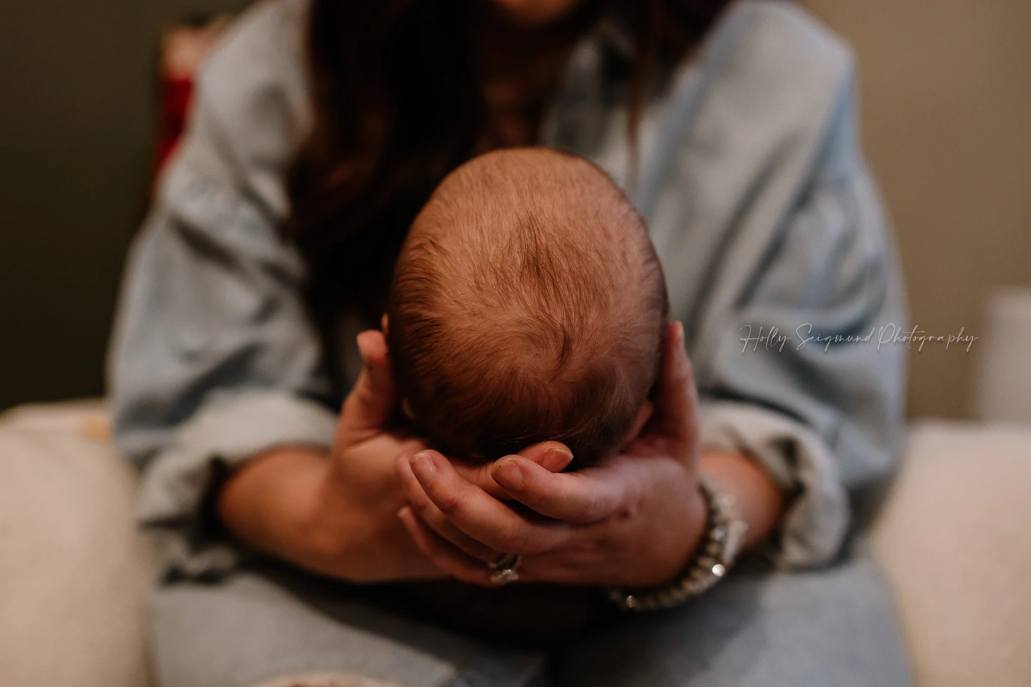 In-home newborn session with baby's head in mom's hands in Central Texas