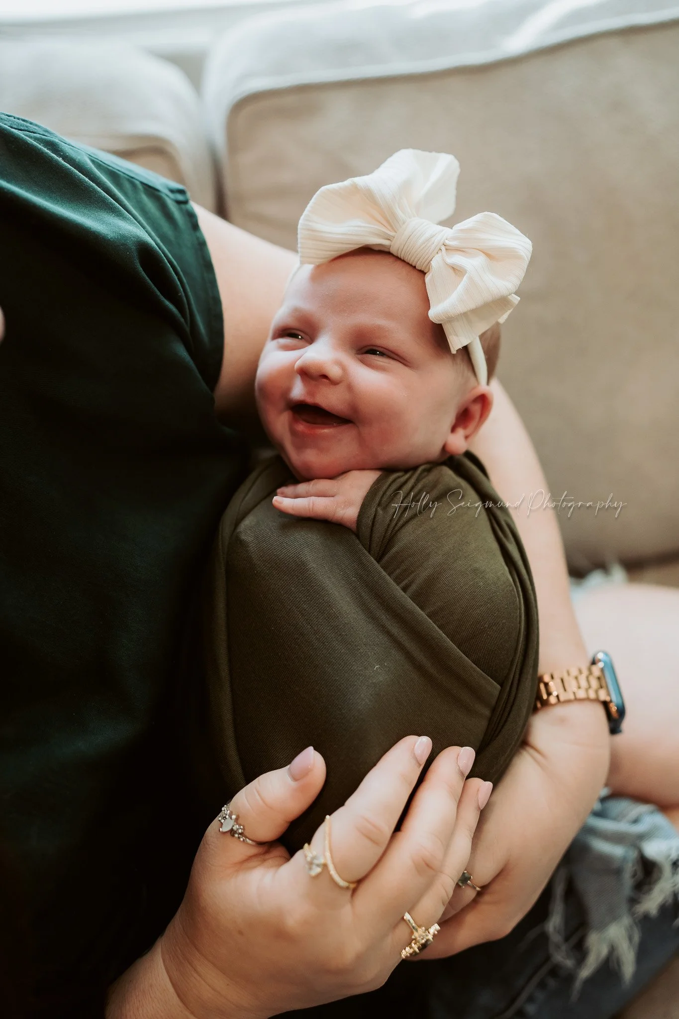 Baby girl wrapped in a green wrap and white bow during a lifestyle newborn session in Austin, Texas