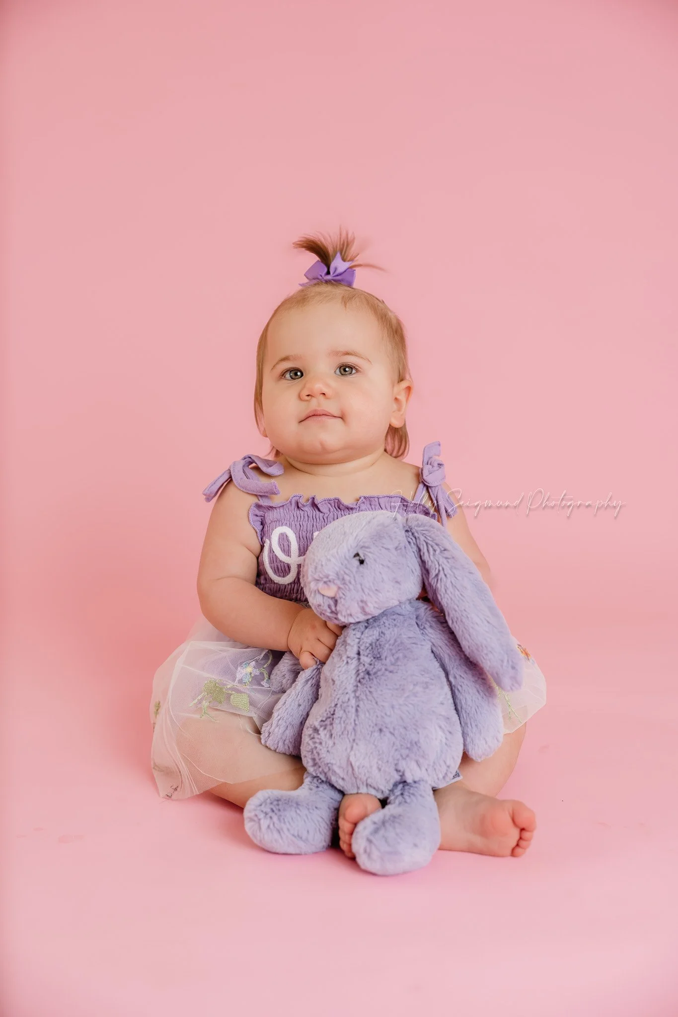 Girls first birthday photos with her stuffed animal in a studio with flash photography on pink paper near Elgin, Texas