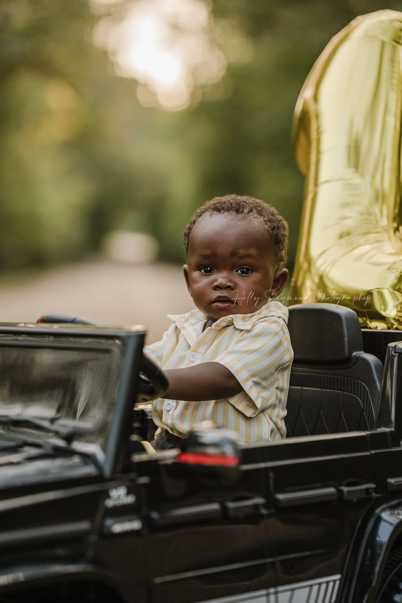 First birthday photo for a little boy driving his favorite toy car 