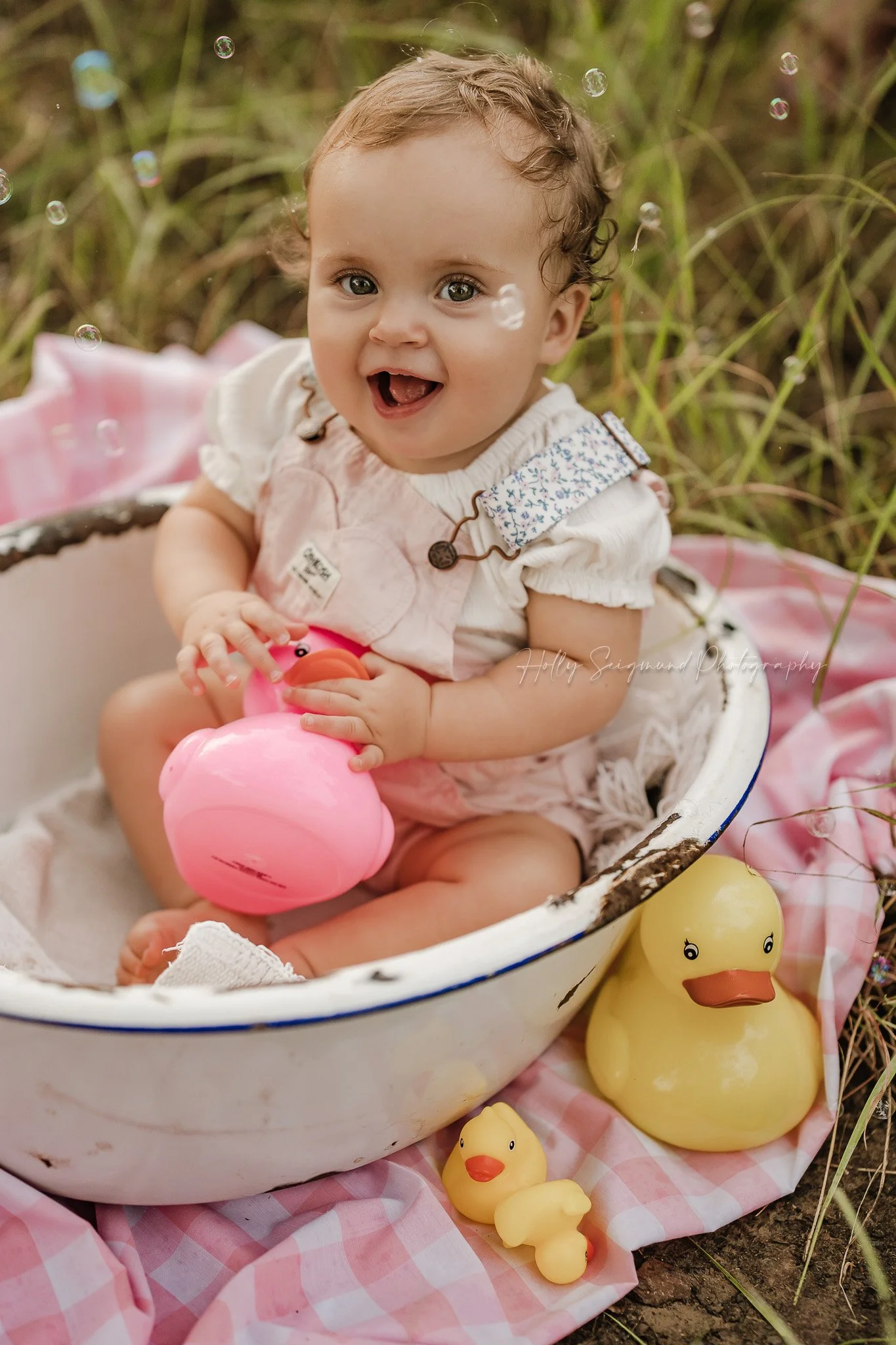 Baby girls first birthday photos with rubber ducks in a metal tub in the grass in Lee County Texas