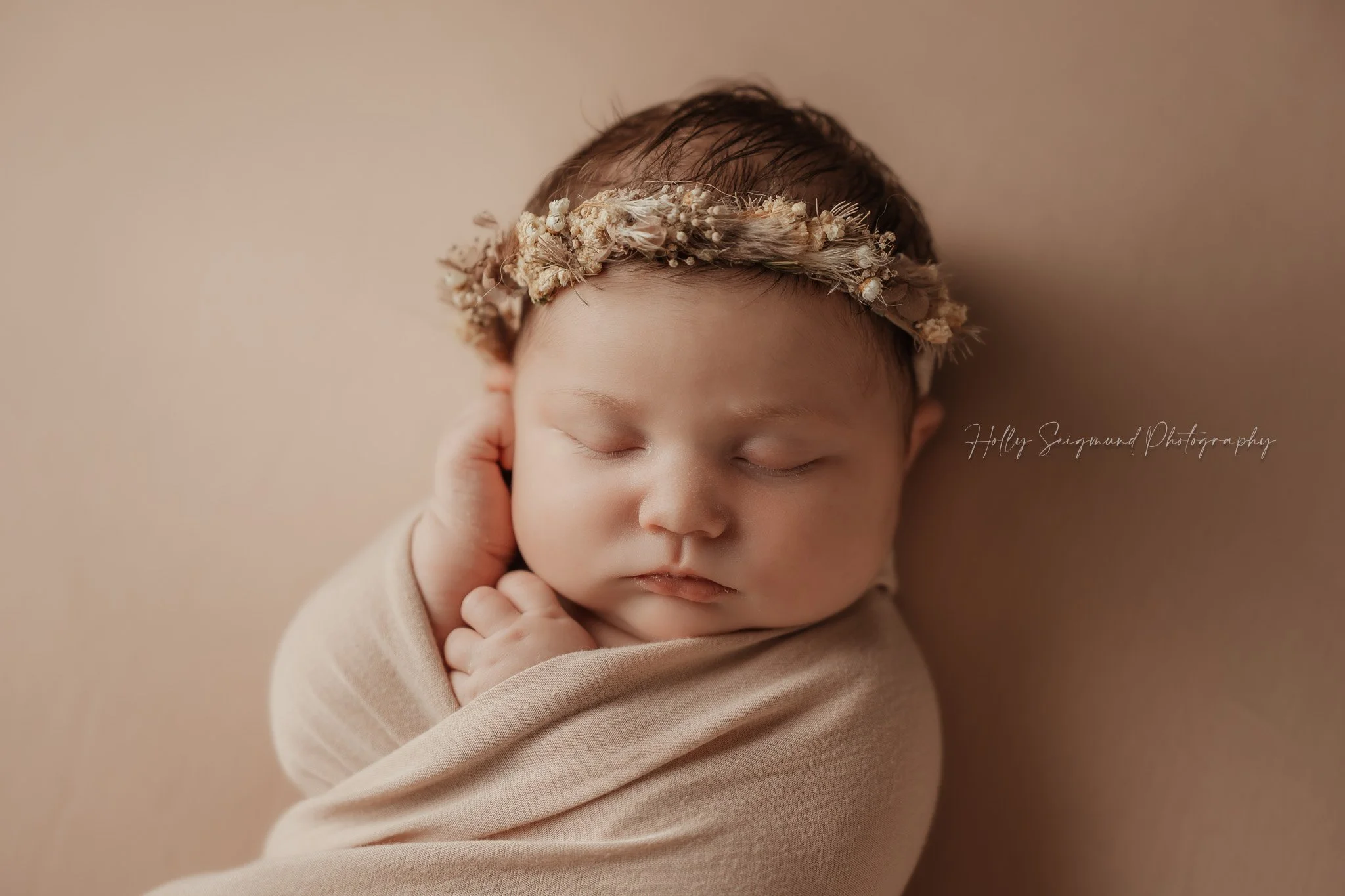 Newborn baby girl with a floral crown and wrapped up with a matching backdrop in Central Texas