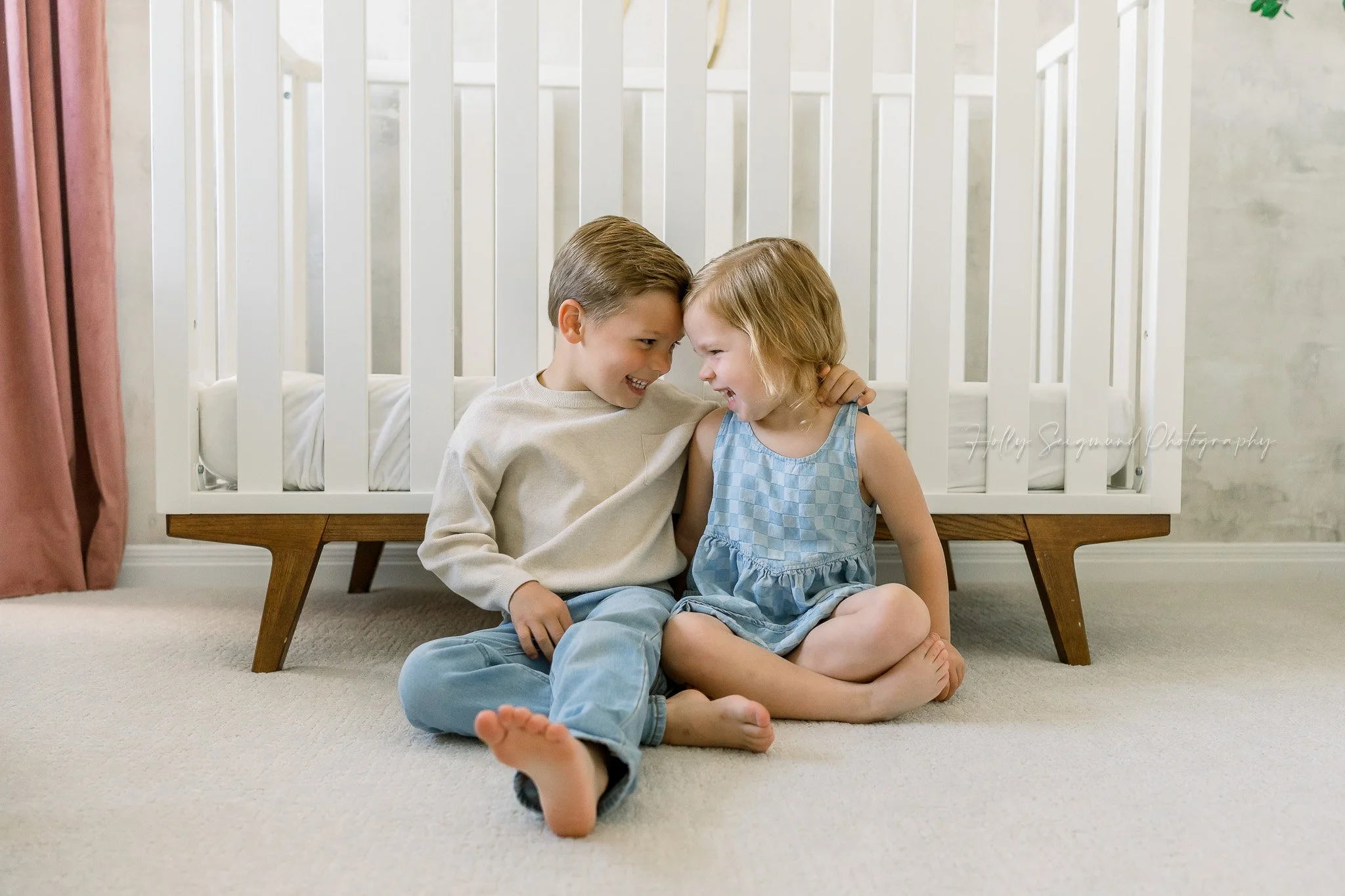 siblings in front of nursery crib during an in-home newborn session in Central Texas