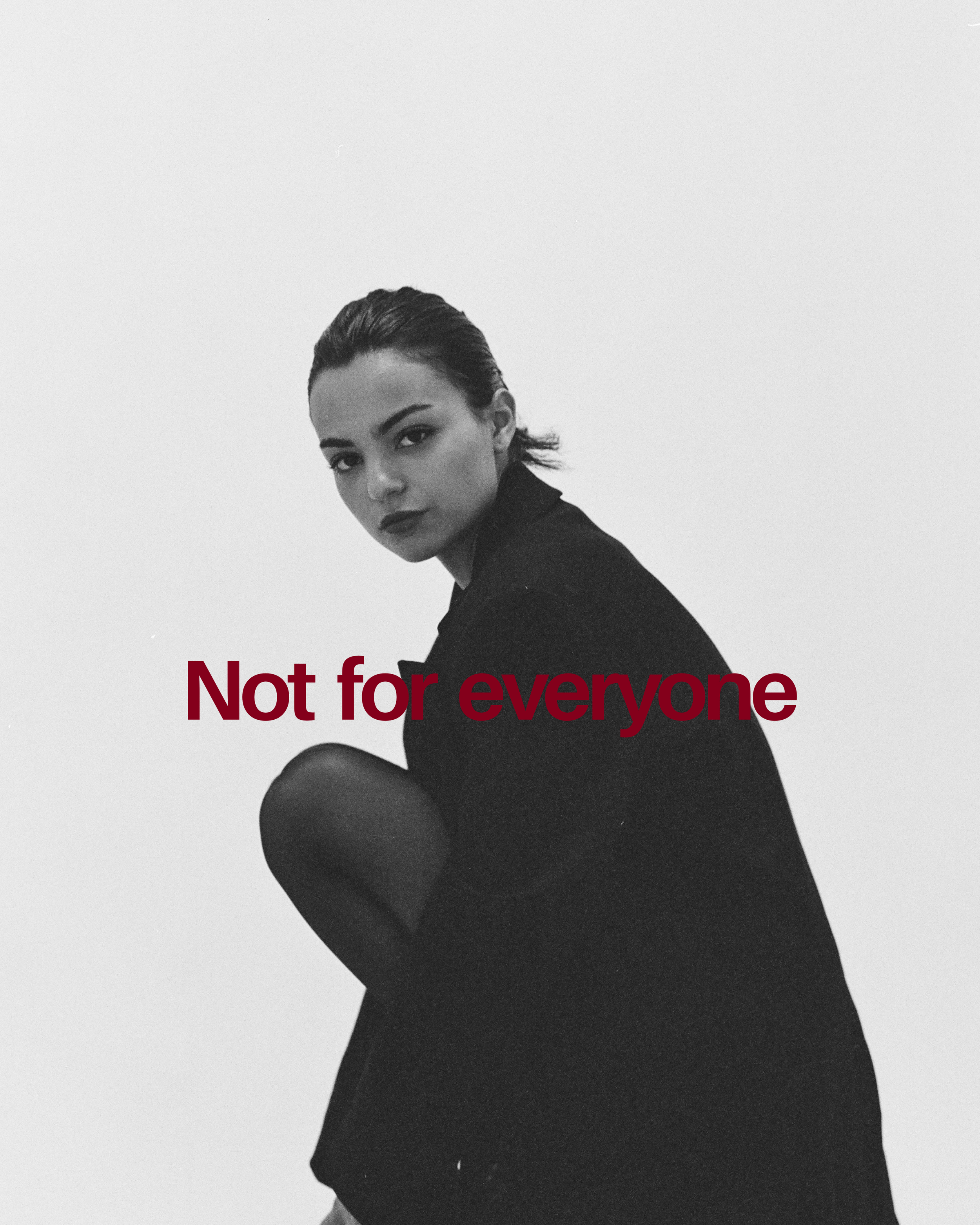 Black and white photo of a woman with dark hair, sitting against a plain wall, with the text 'Not for everyone' in red and burgundy across the middle.