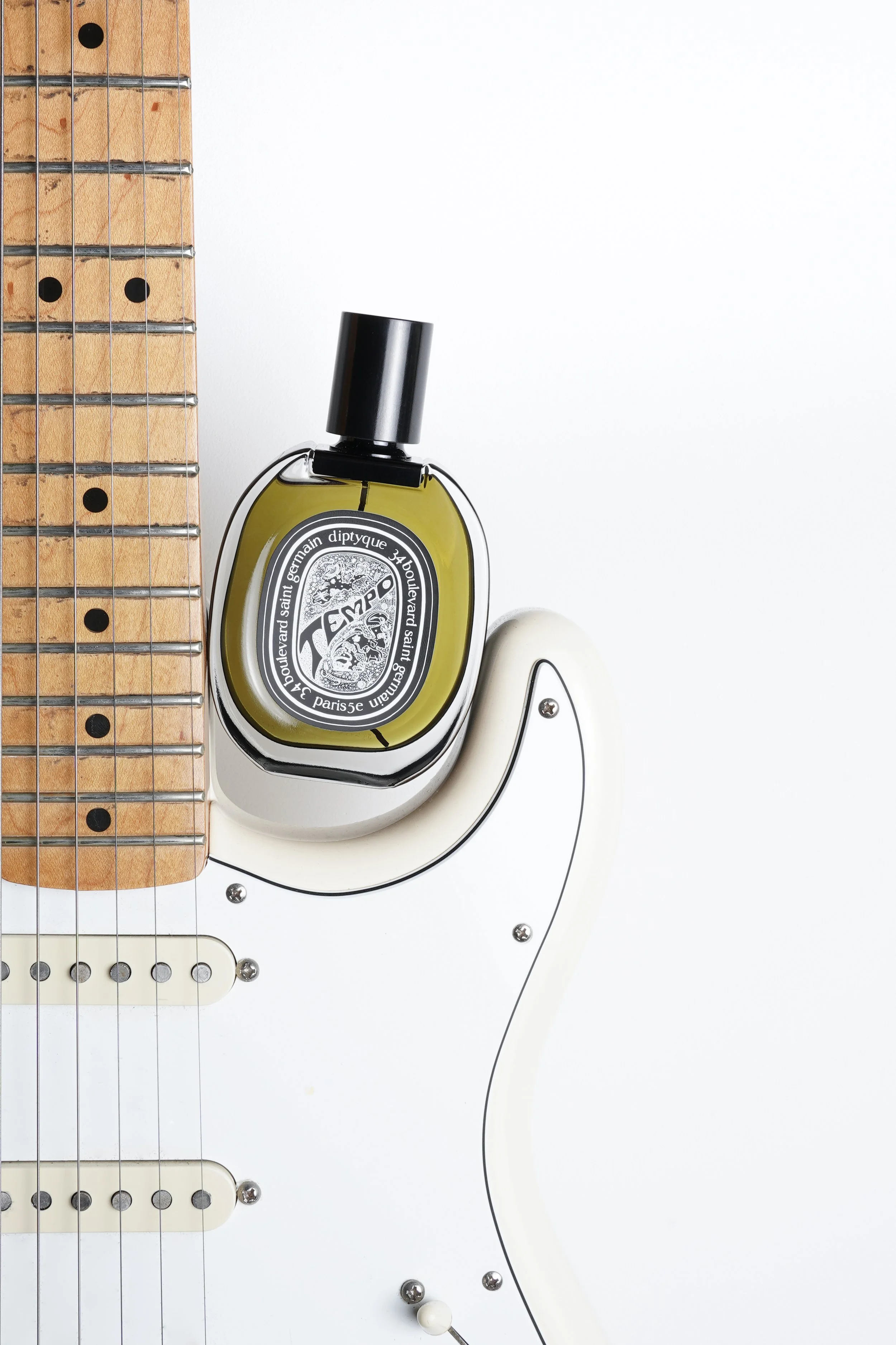 Shooting Diptyque Tempo fragrance placed on the body of the guitar.