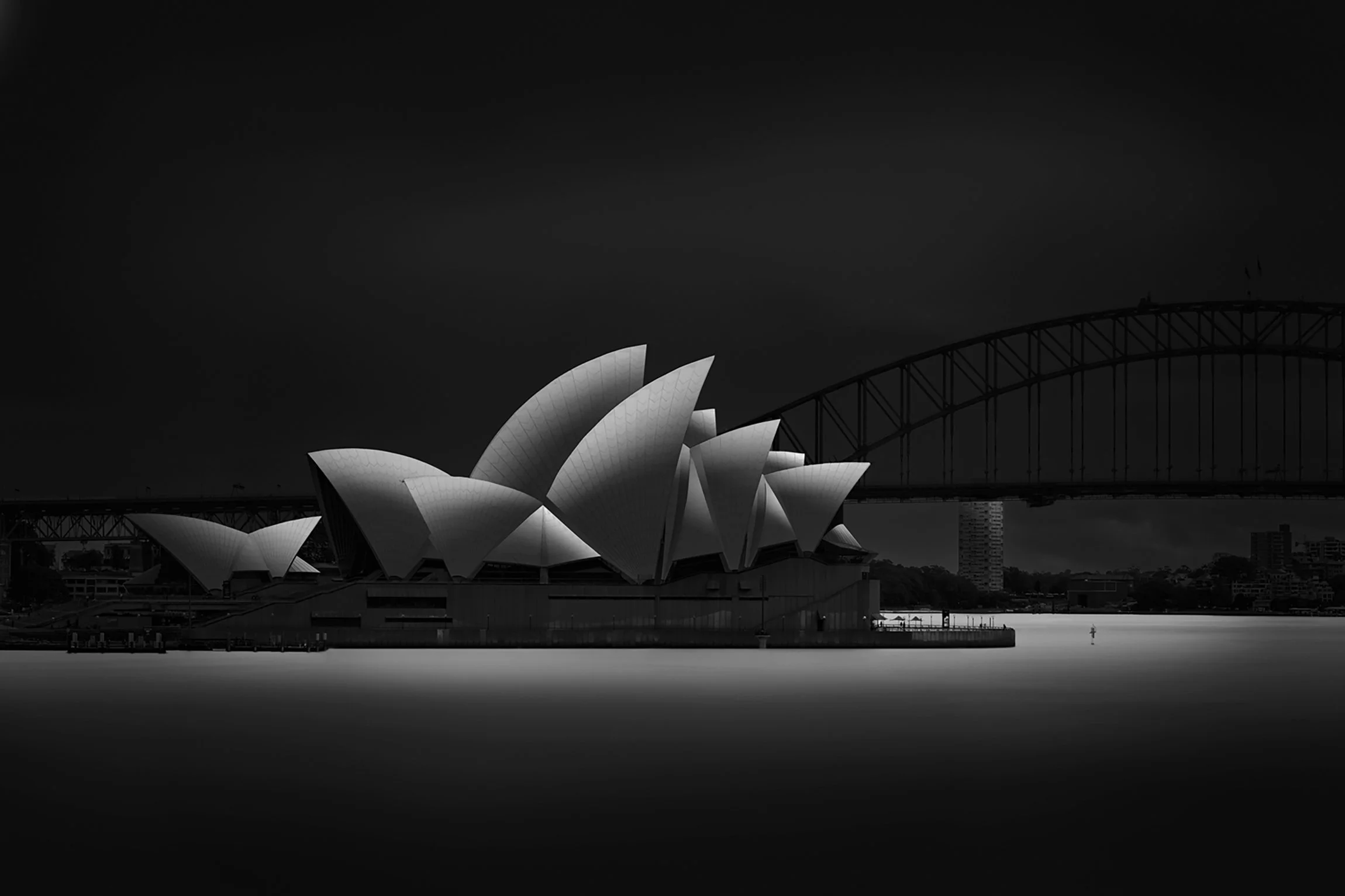 The iconic sails of the Sydney Opera House stand poised on the harbour’s edge, a timeless presence beside the Sydney Harbour Bridge. Anchored in place yet commanding the skyline, her sweeping forms quietly draw the eye, demanding attention without ev