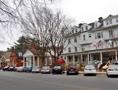 Row of houses with parked cars in front, leafless trees, and overcast sky. Main Street in Stockbridge. Red Lion Inn.