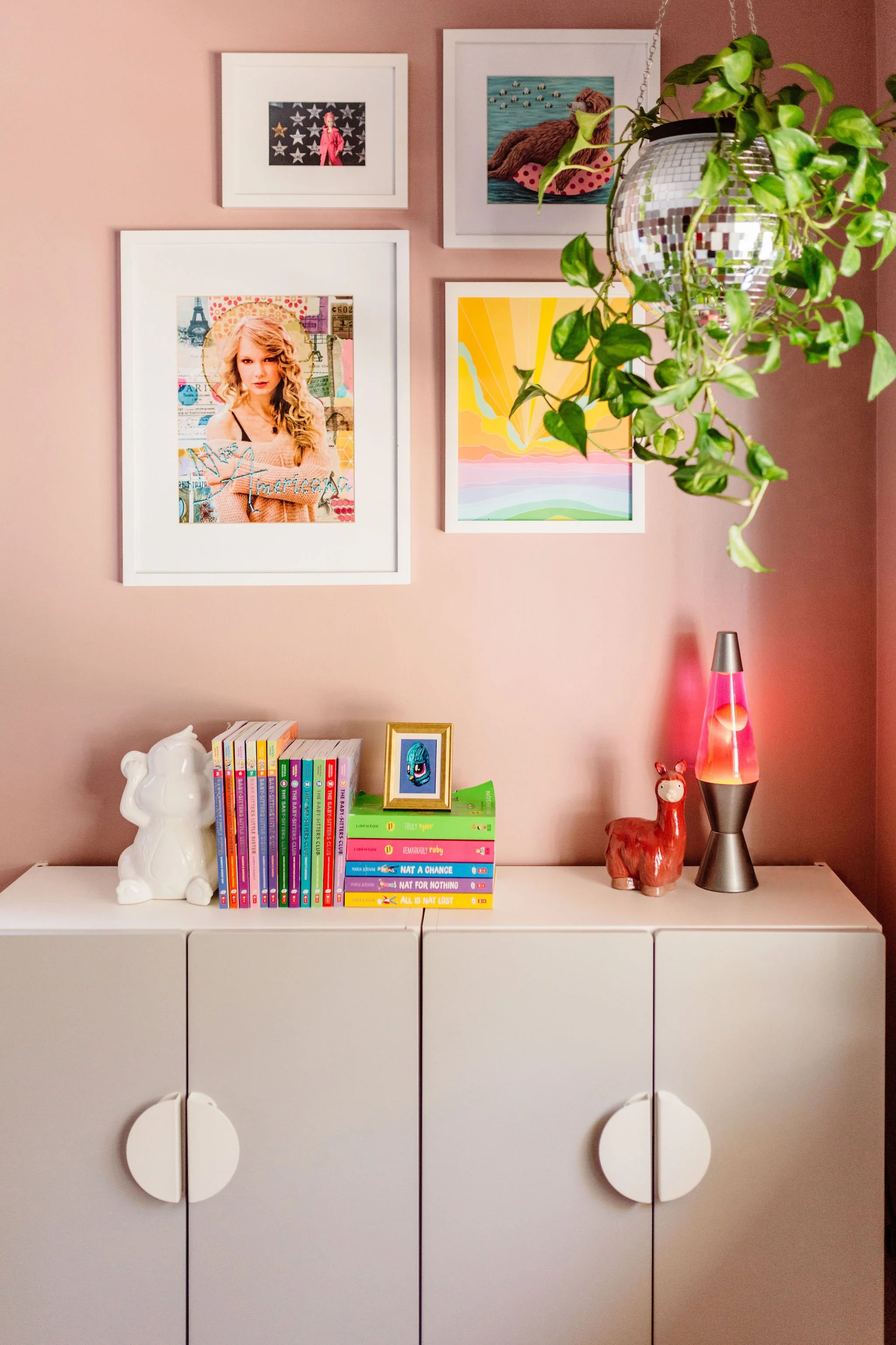 Stylish girl's room with a curated art wall against soft dusty pink walls.