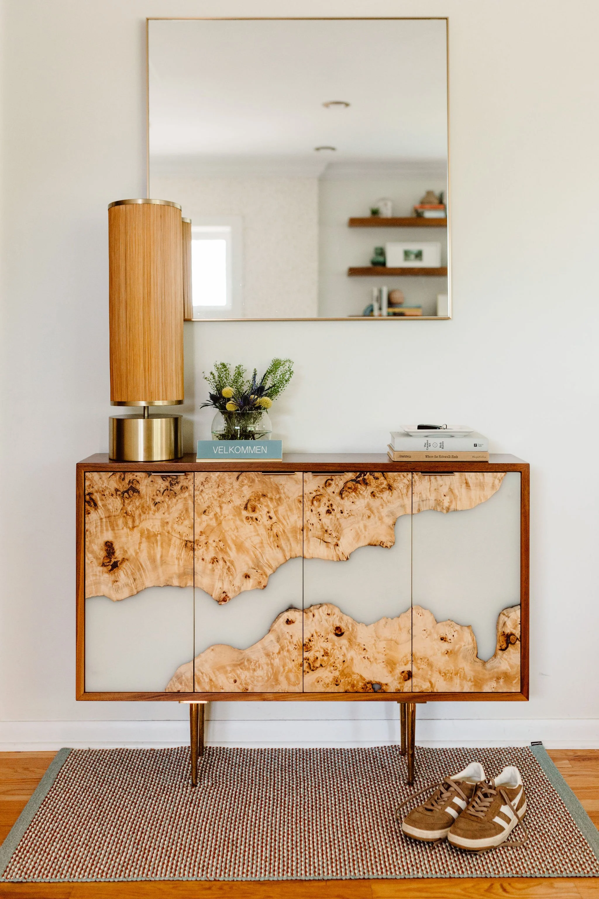 Custom burl wood credenza and sleek mirror in modern foyer.