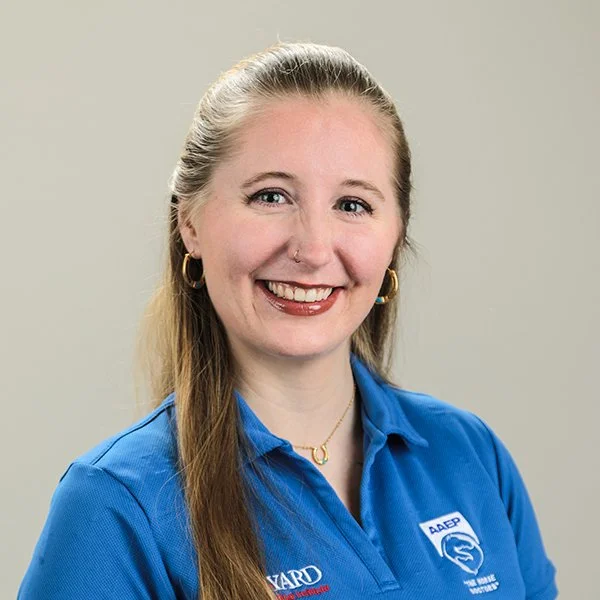 A classroom presentation with a woman standing by the projector screen, teaching a group of students. The screen displays advice about networking, skill development, and hands-on experience. Students are seated at desks, paying attention.