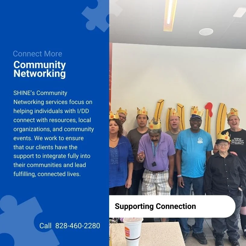 Group of people wearing paper crowns at a community event, standing in front of a wall with large red and yellow letters. There is a sign on the left side with information about community networking services.