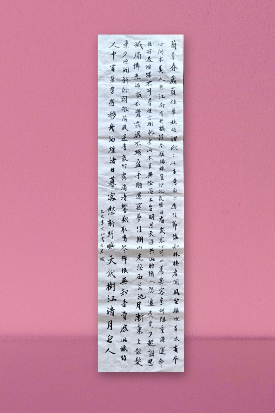 Vertical scroll of Chinese calligraphy on white paper against a pink textured background.
