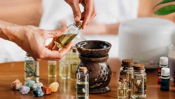 Person dispensing drops of essential oil or medicine from a small amber glass bottle into their hand in a dark environment.