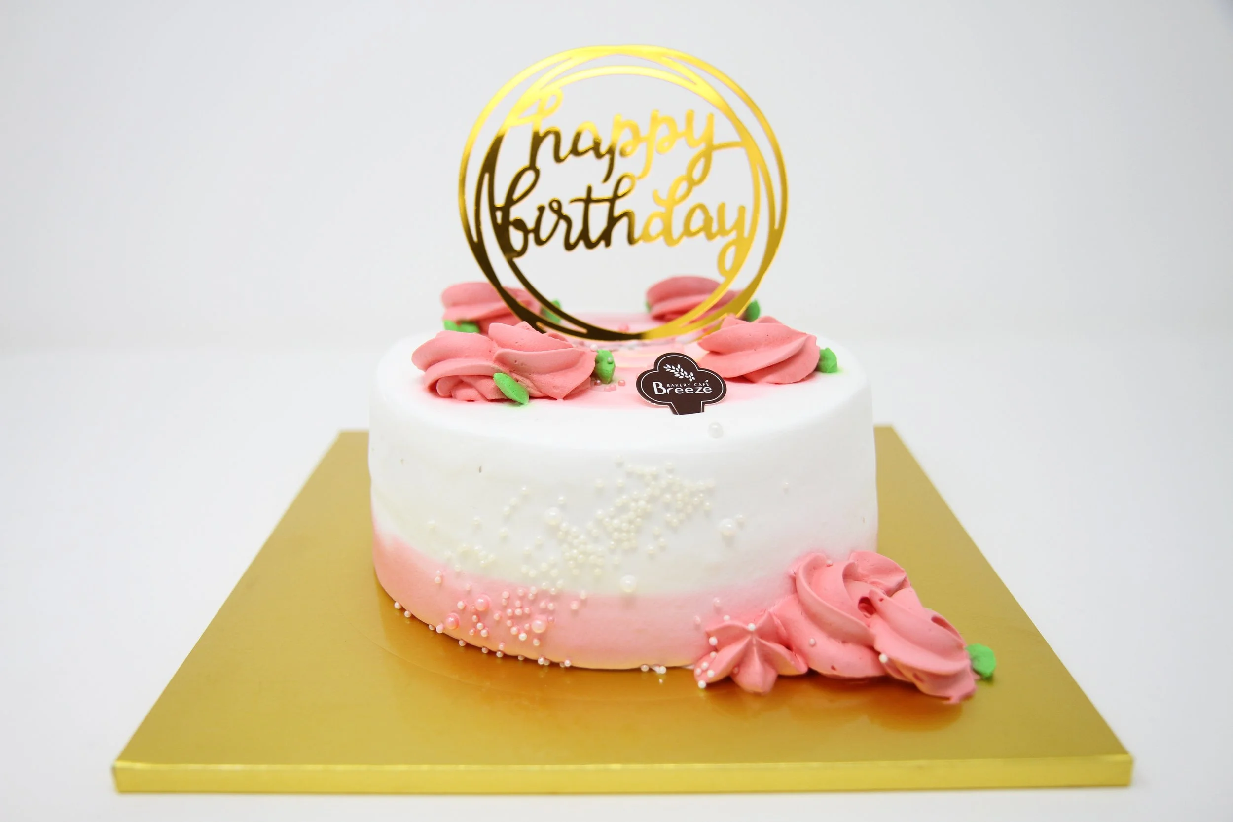 'Happy Birthday' decorated cake with coral fresh cream flowers on white fruit cake.