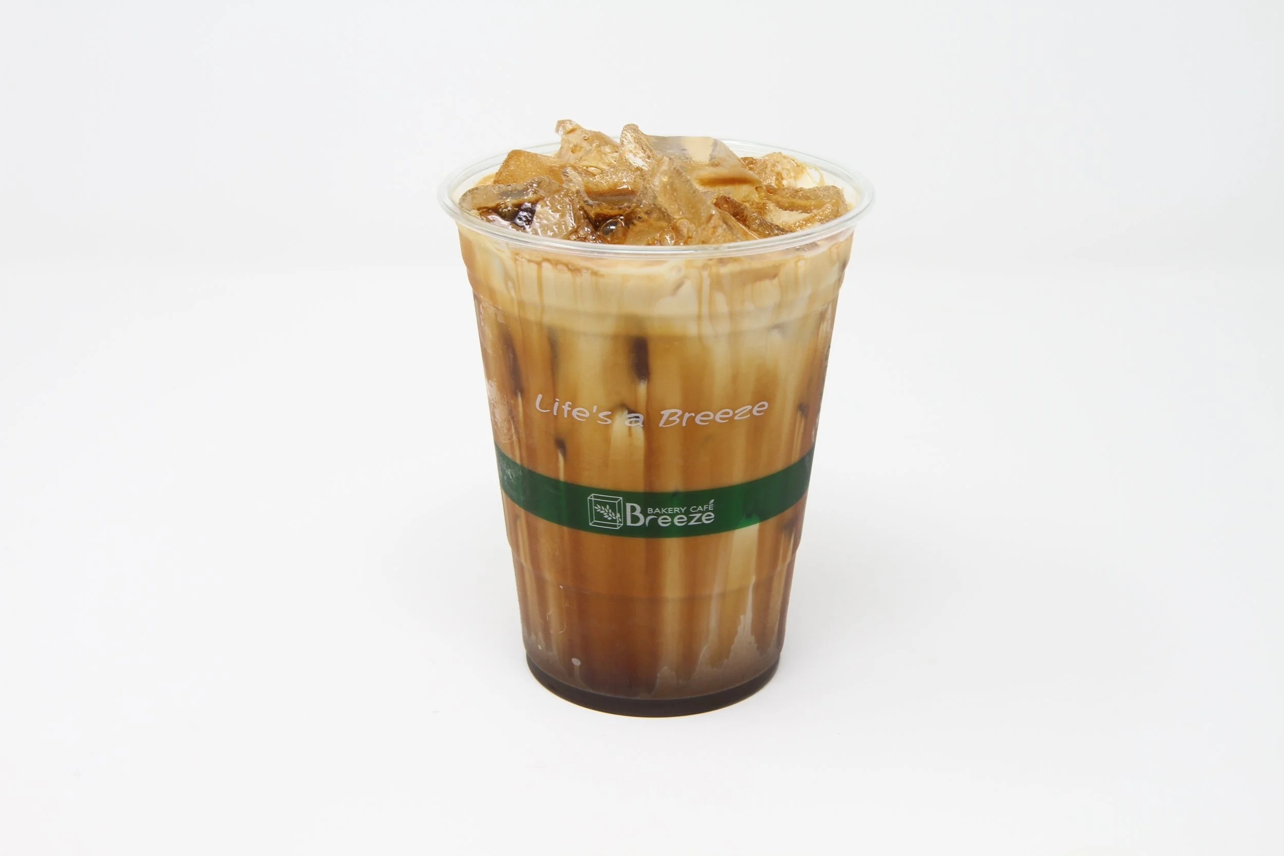 Iced coffee drink in clear plastic cup, sweet coffee sauce is dripping from top to the bottom as it mixes with the milk.