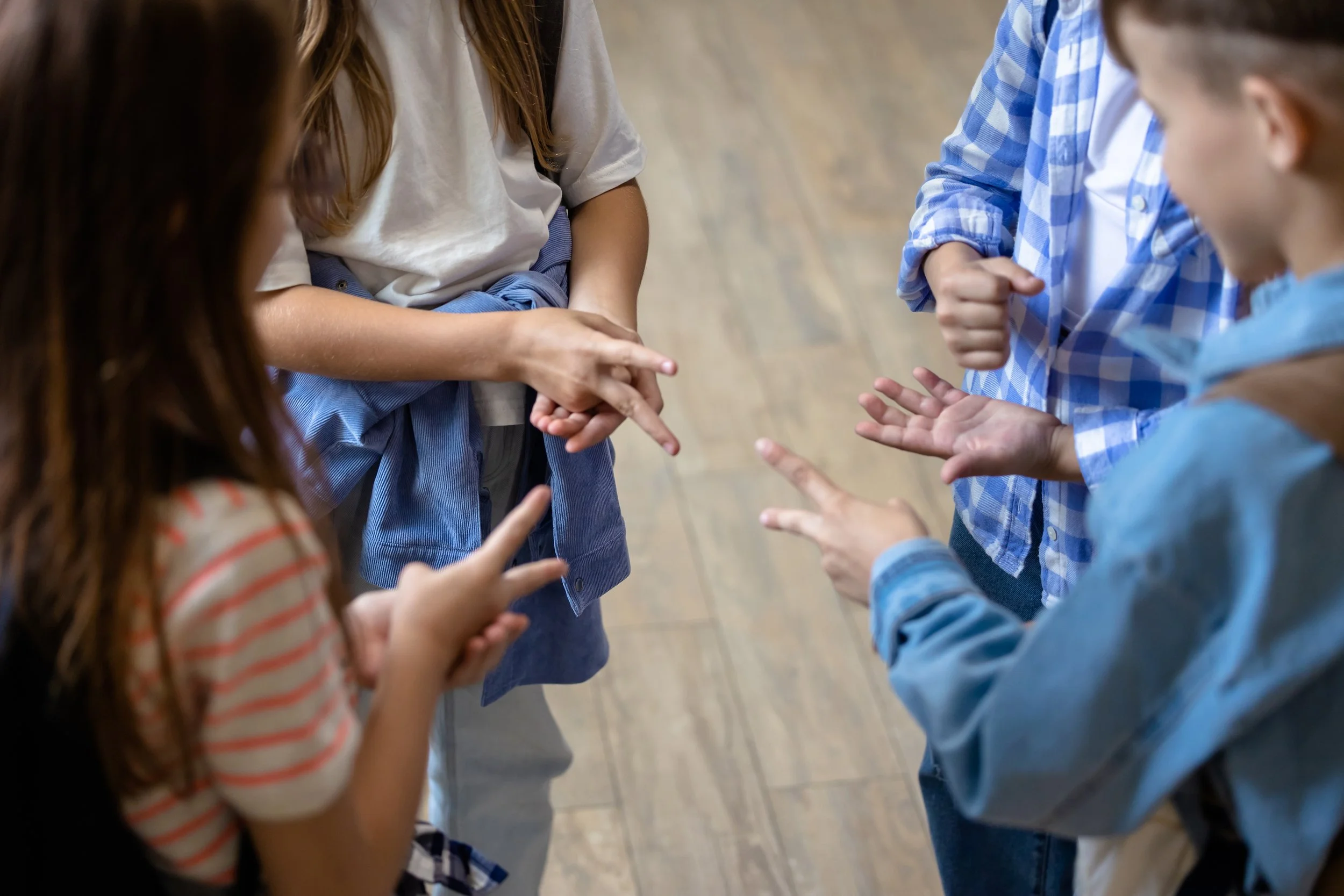 Children in a circle having a conversation, with some children gesturing with their hands.