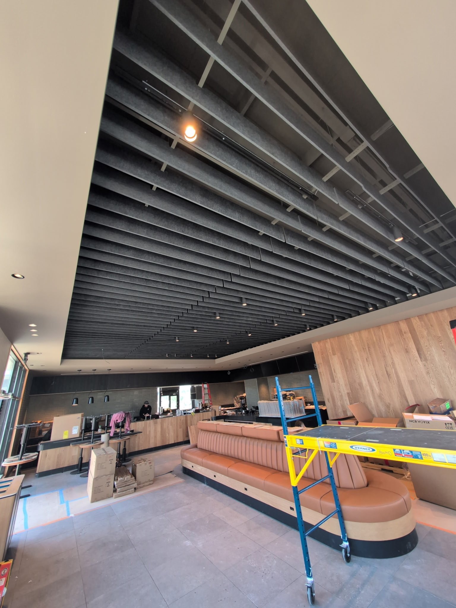 Interior of a restaurant or cafe under construction with a curved booth, scaffolding, and work materials.