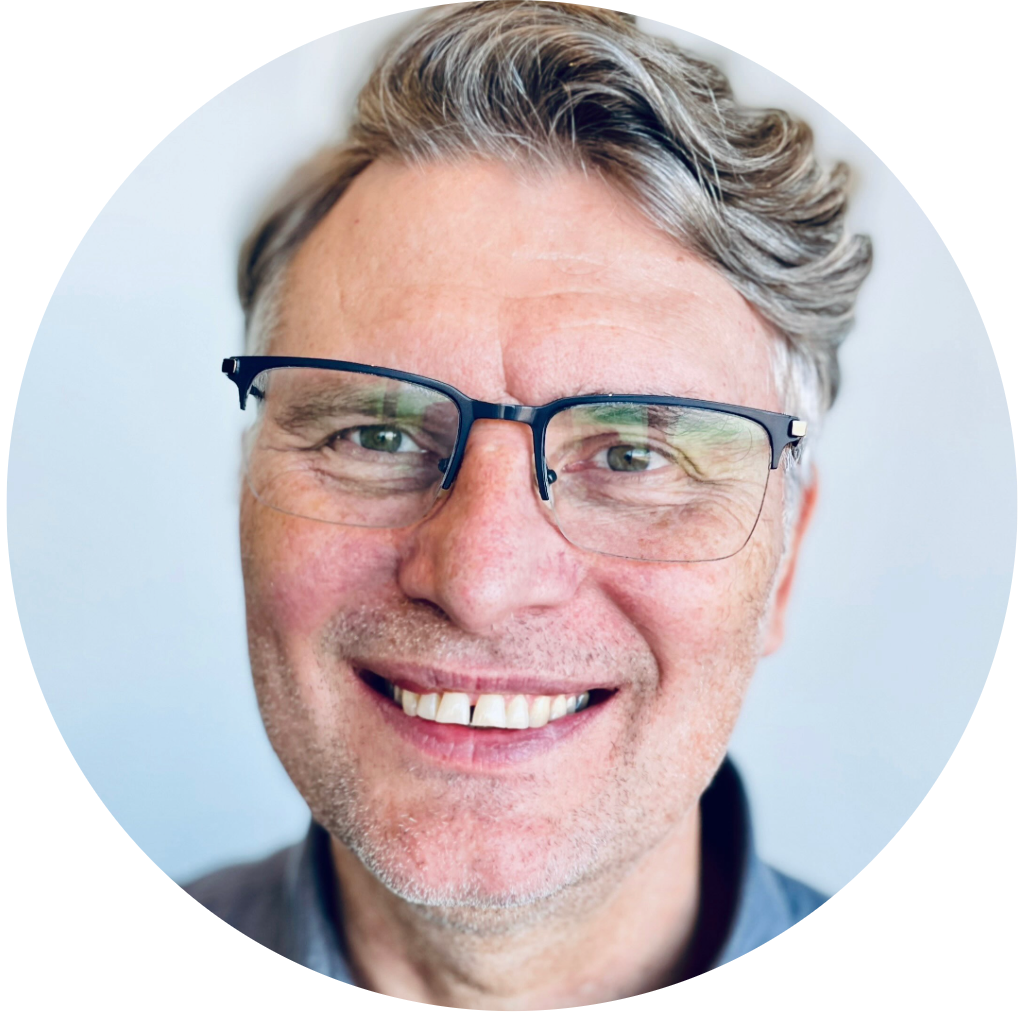 Close-up of a smiling middle-aged man with glasses and gray hair.