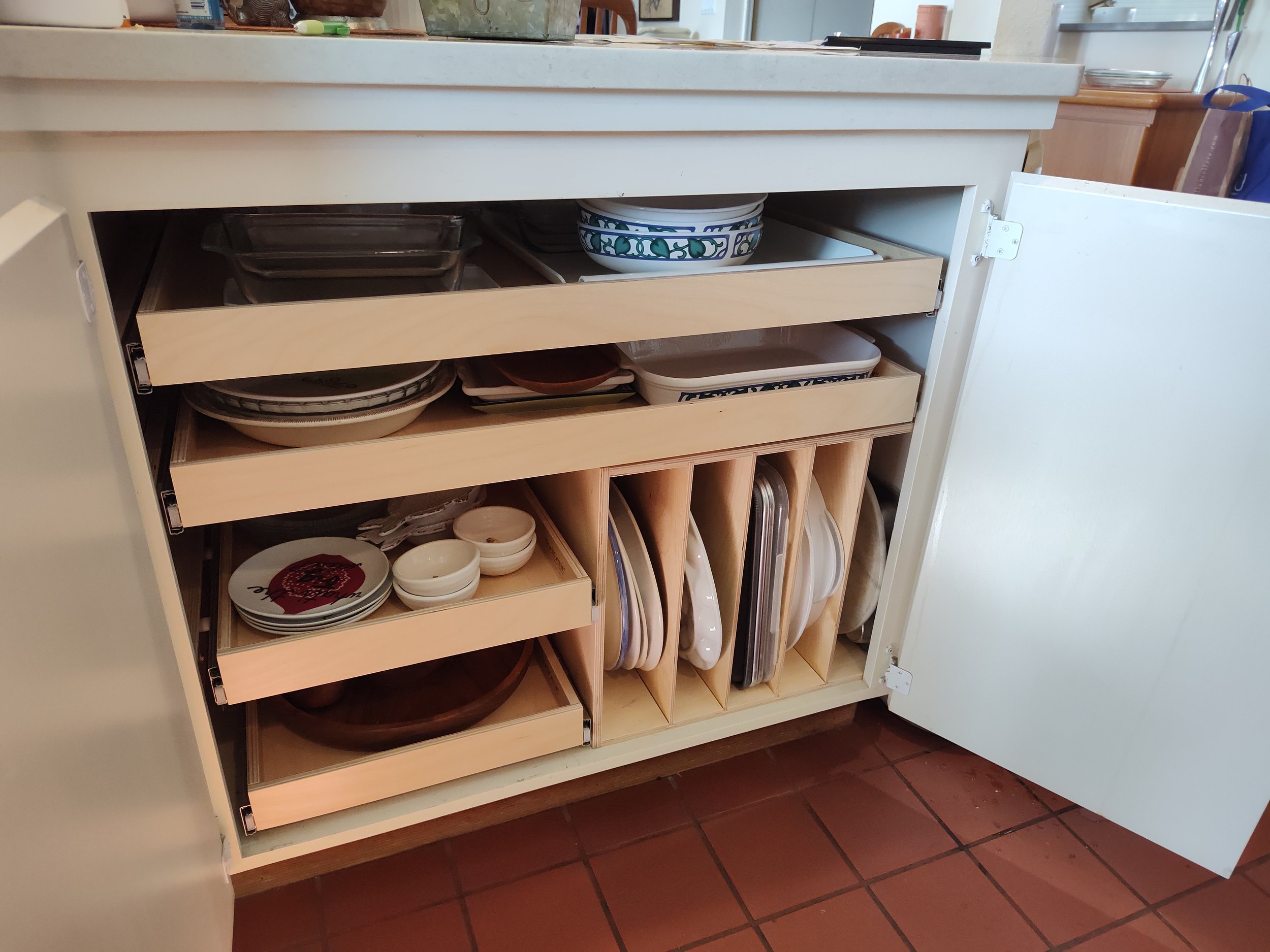 Open kitchen cabinet with shelves holding plates, bowls, and cutting boards.