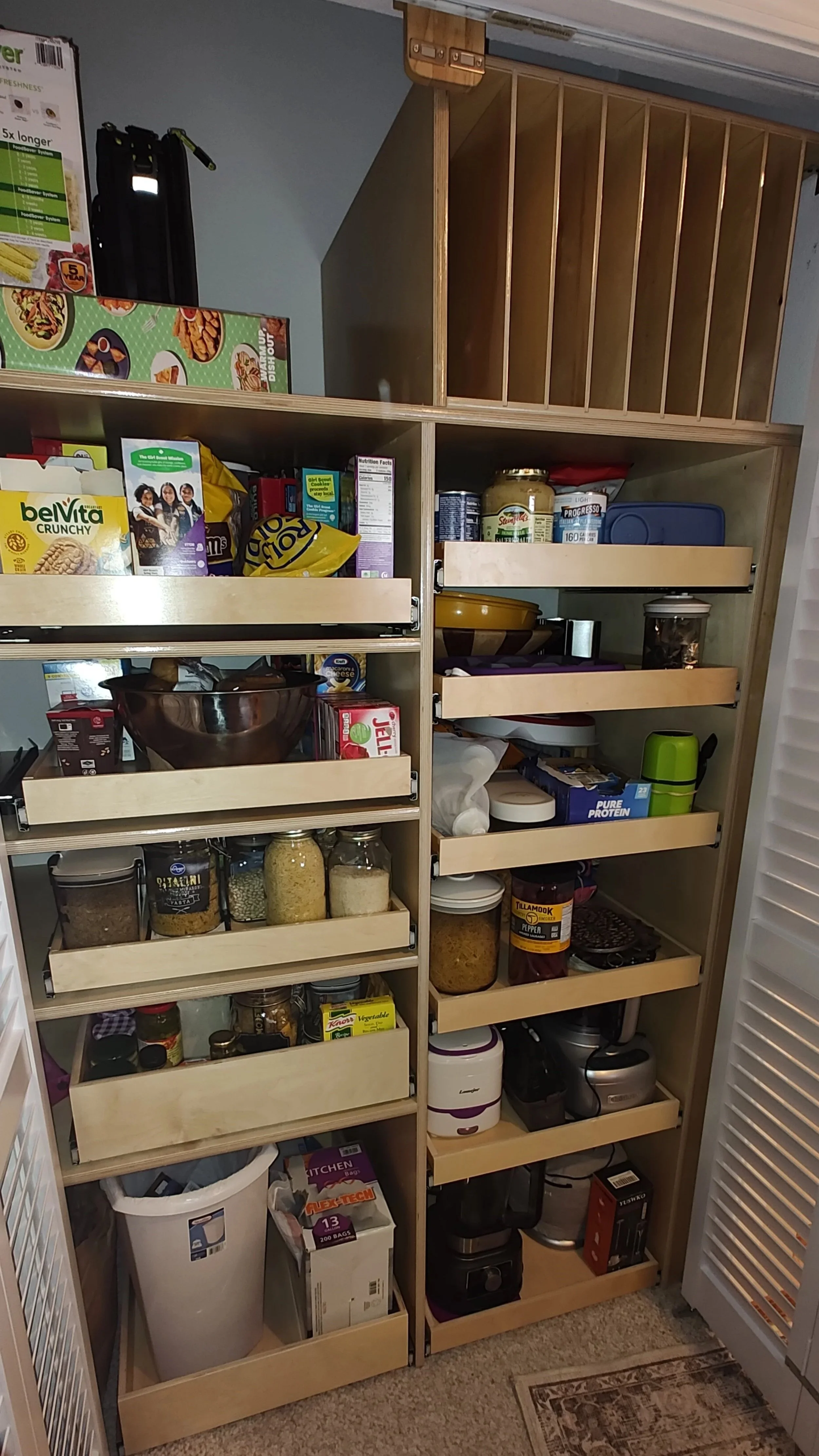 Open pantry shelves filled with food storage containers, jars, and kitchen appliances.